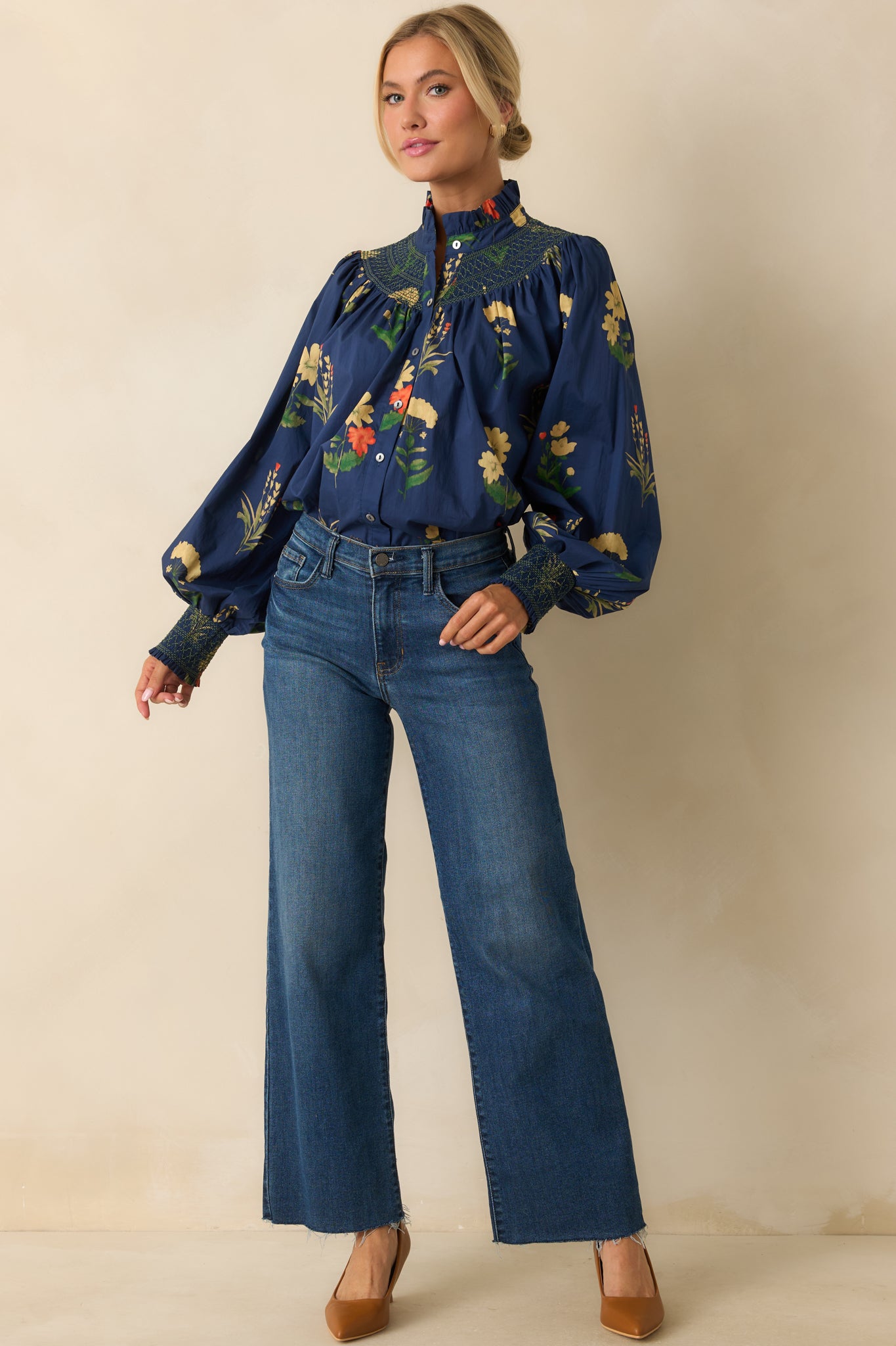 Navy woven blouse with a floral print, ruffled stand collar, and button-front closure.