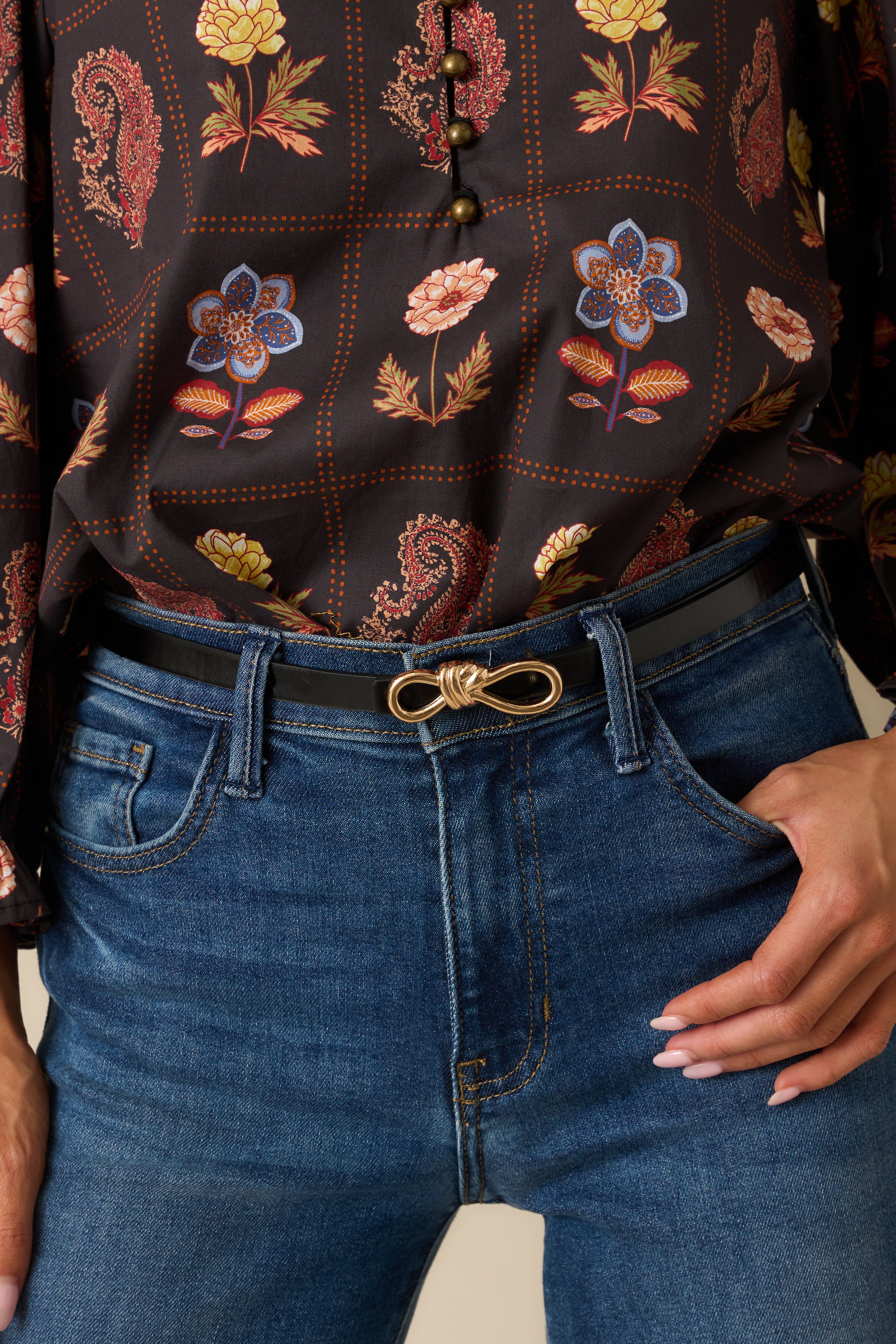 Close-up of the gold rope-inspired interlocking buckle and textured faux leather material.