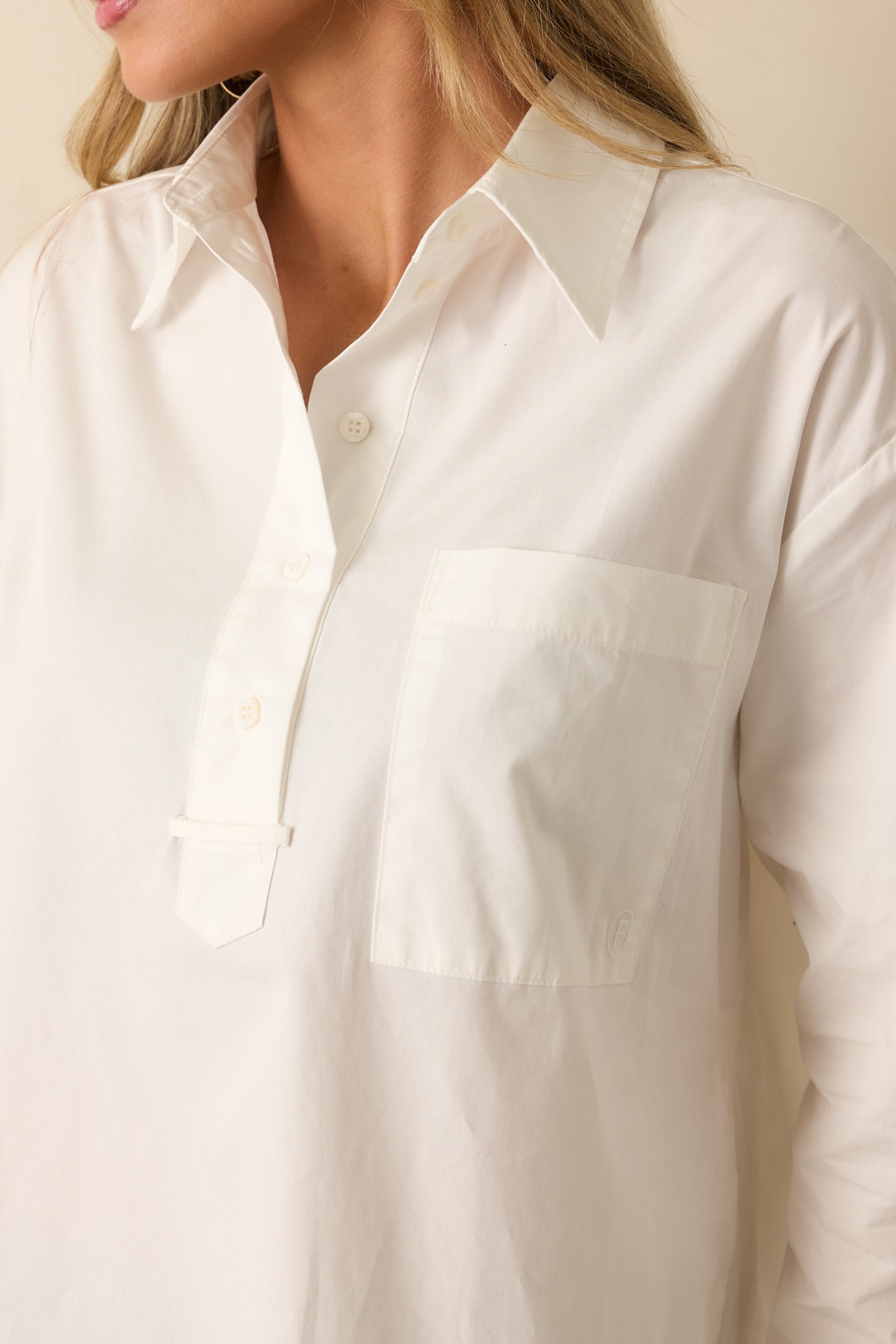 Detailed shot showing the fabric texture, buttons, and patch pocket of the white cotton blouse.