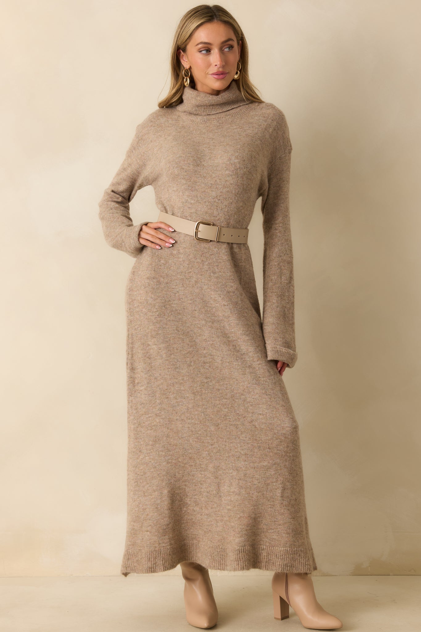 Front view of the beige knit maxi dress featuring a turtleneck neckline, long sleeves, and a relaxed, flowing silhouette.
