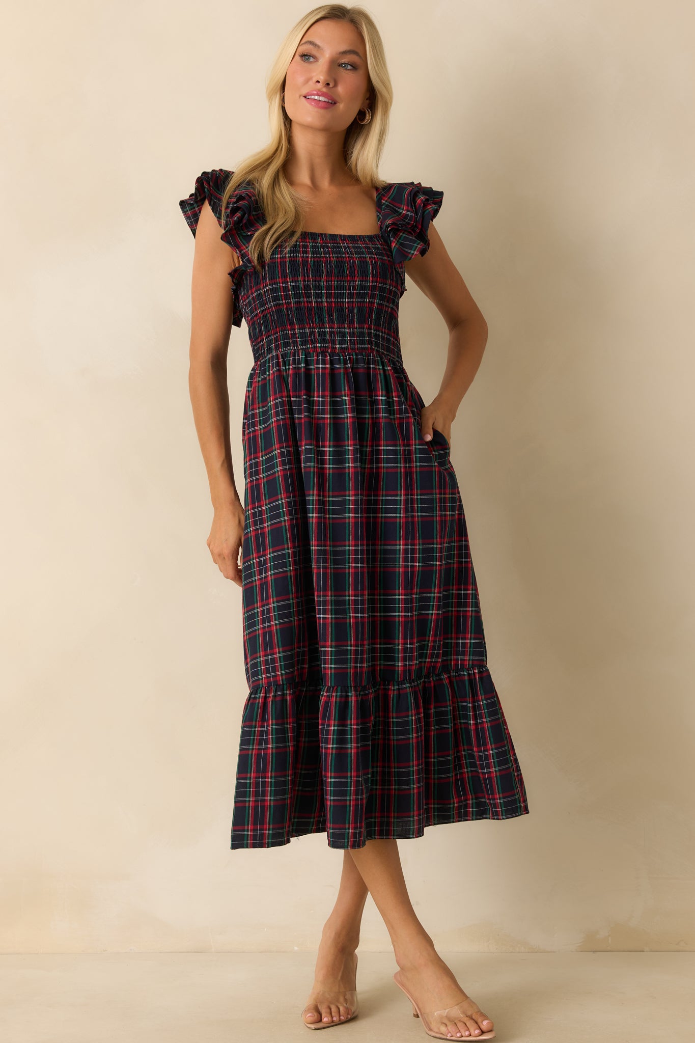 Front view of navy dress featuring a smocked bodice, flutter sleeves, and flowing tiered skirt.