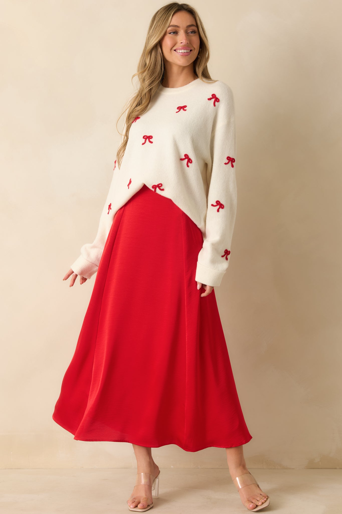 Cozy white pullover sweater with relaxed silhouette and scattered embroidered red bows for a holiday-inspired look.