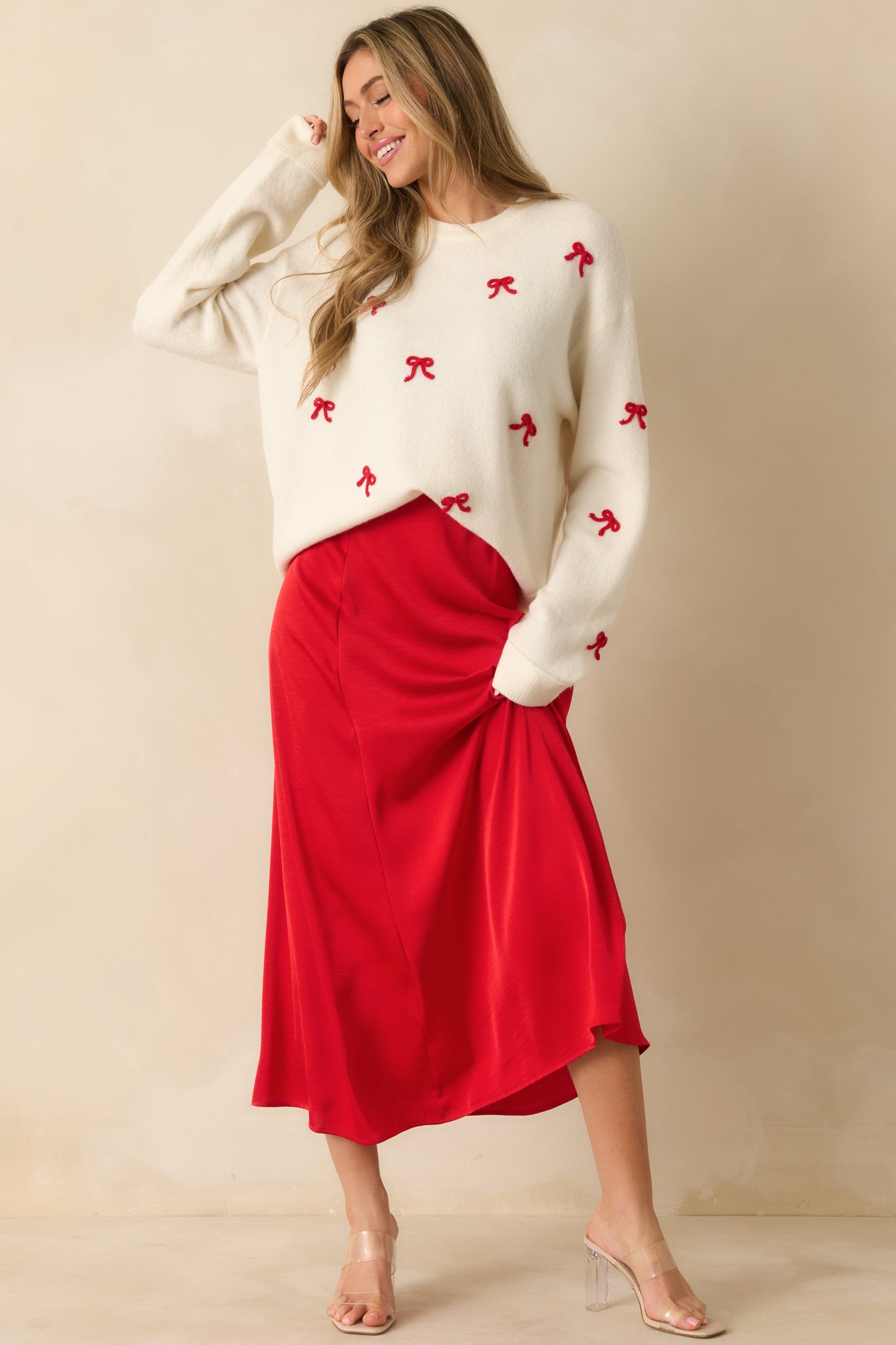 White knit pullover with crew neckline, long sleeves, and playful embroidered red bows for a holiday-ready look.