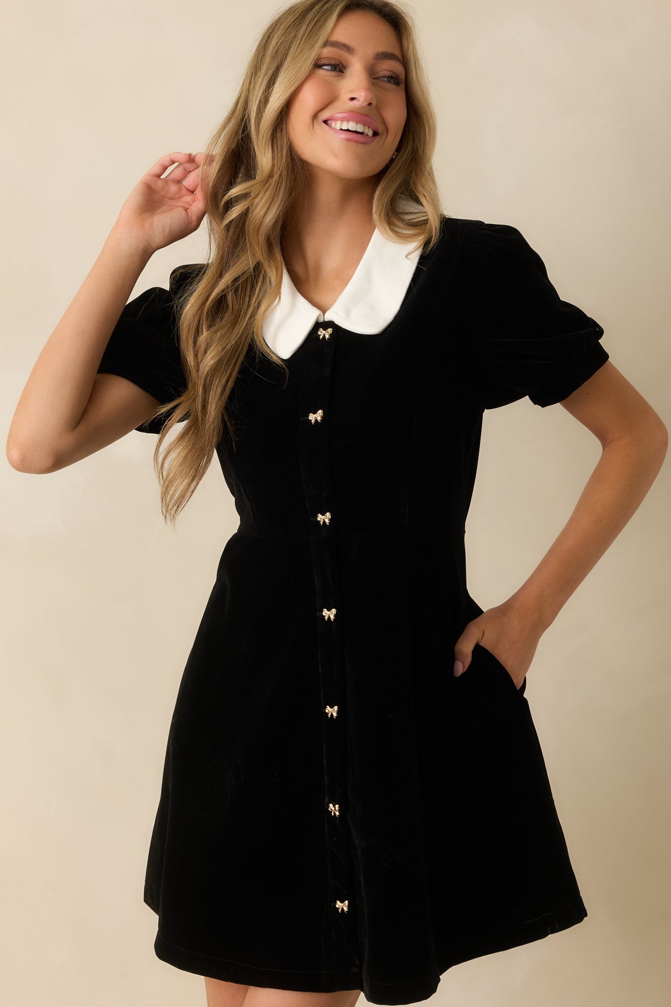 View of the velvet mini dress highlighting the white Peter Pan collar and gold buttons.