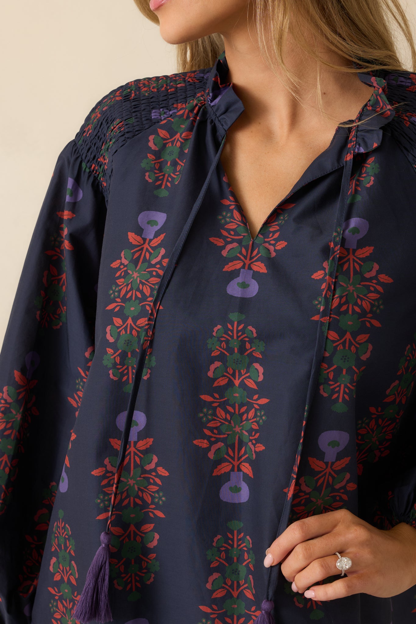 Close-up detail of the navy multi peasant top showing the floral print, smocking, and tie closure.