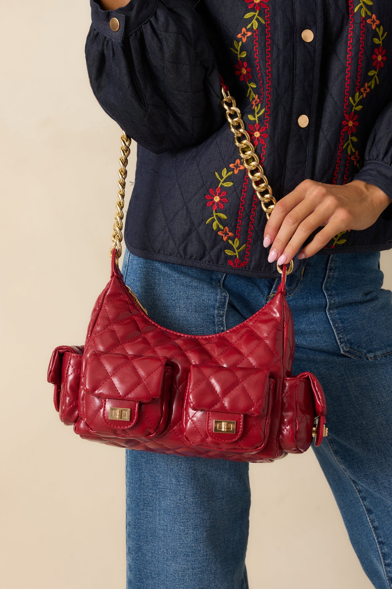 Structured red handbag featuring multiple exterior flap pockets with turn-lock closures and quilted detailing.