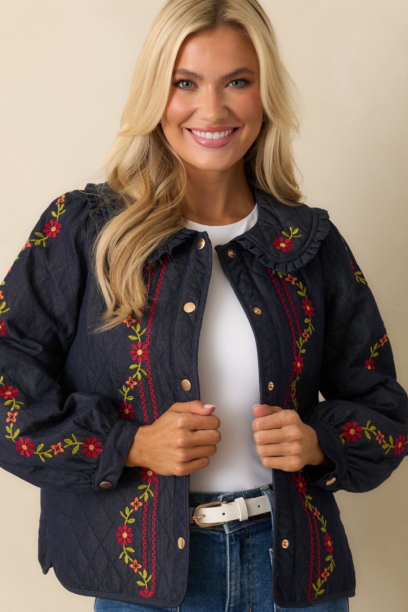 Cropped focus on the ruffled collar and front snap-button closure of the jacket.