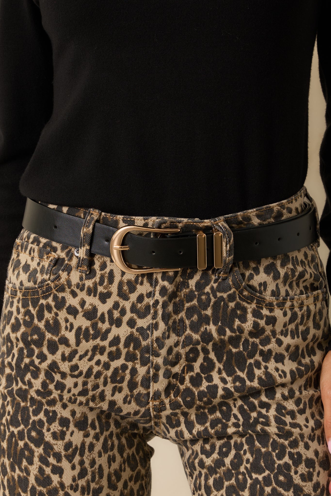 Up close of the black texture and gold hardware on the black belt.