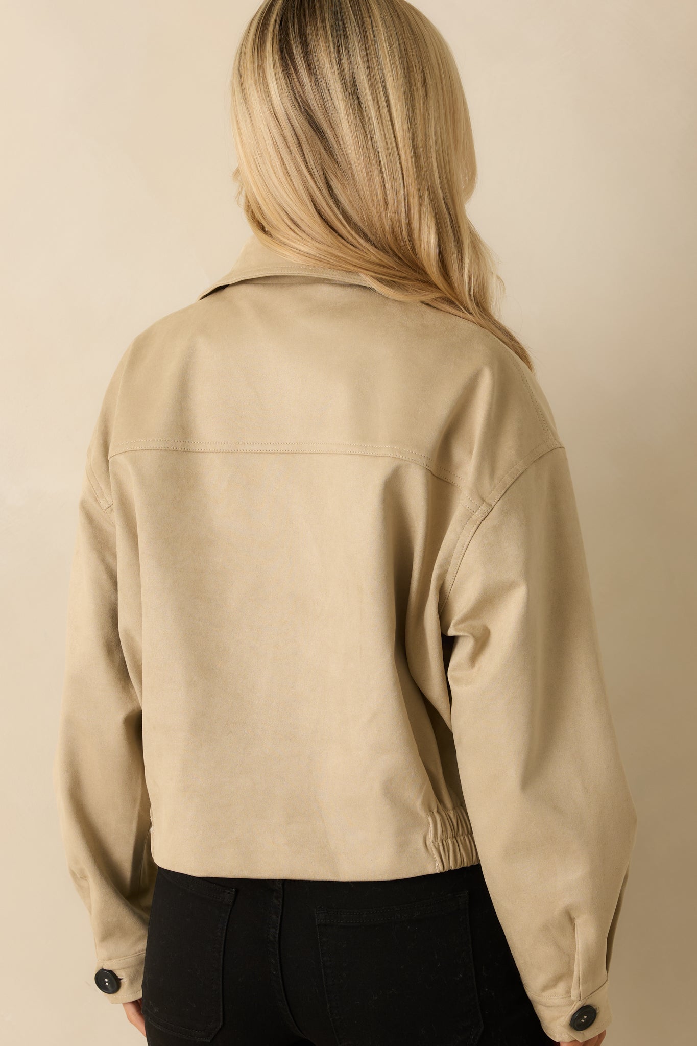 Rear view of the tan cotton jacket showing elasticized back hem and clean lines.