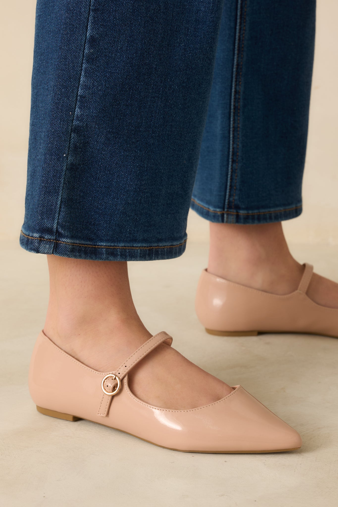 Close-up of the glossy patent faux leather material and silver buckle strap detail.