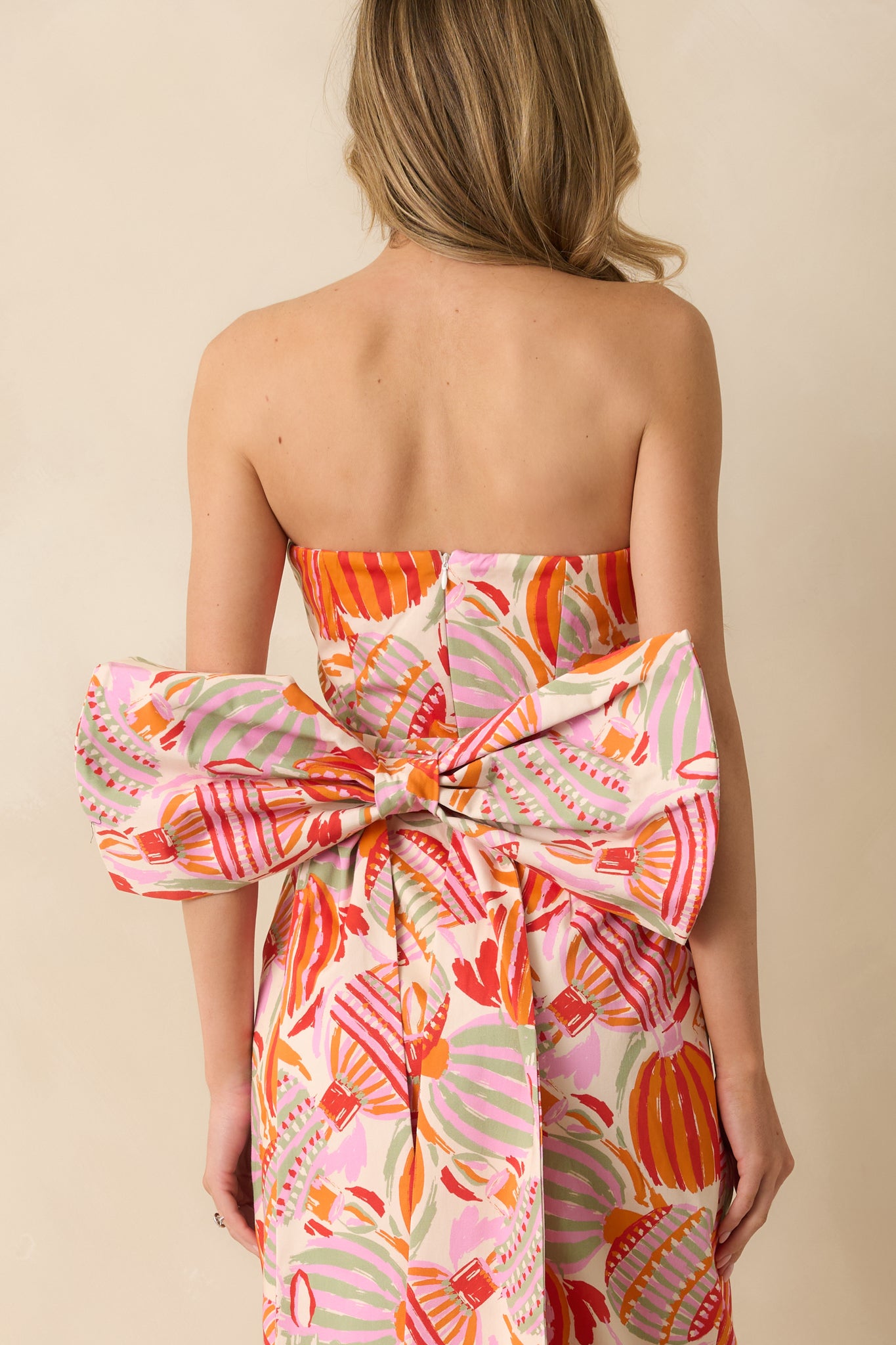 The dress shows the structured fit from behind with the bow detail visible above the smooth multicolor fabric.