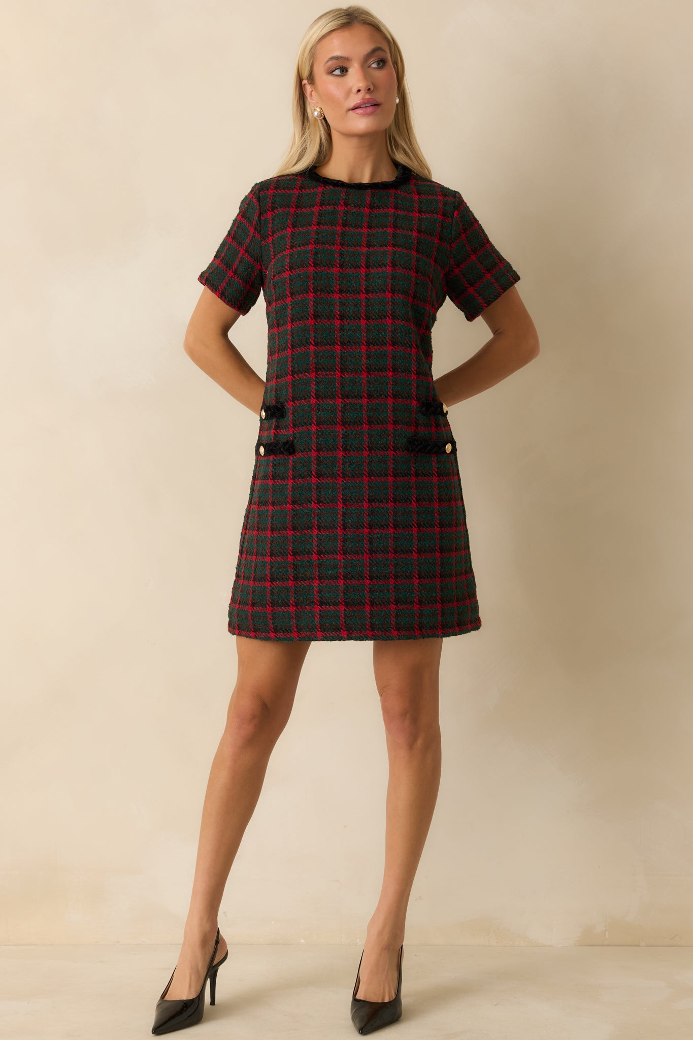 Green and red plaid shift dress displaying its easy, tailored fit and the contrast-trim pockets with gleaming gold button touches.