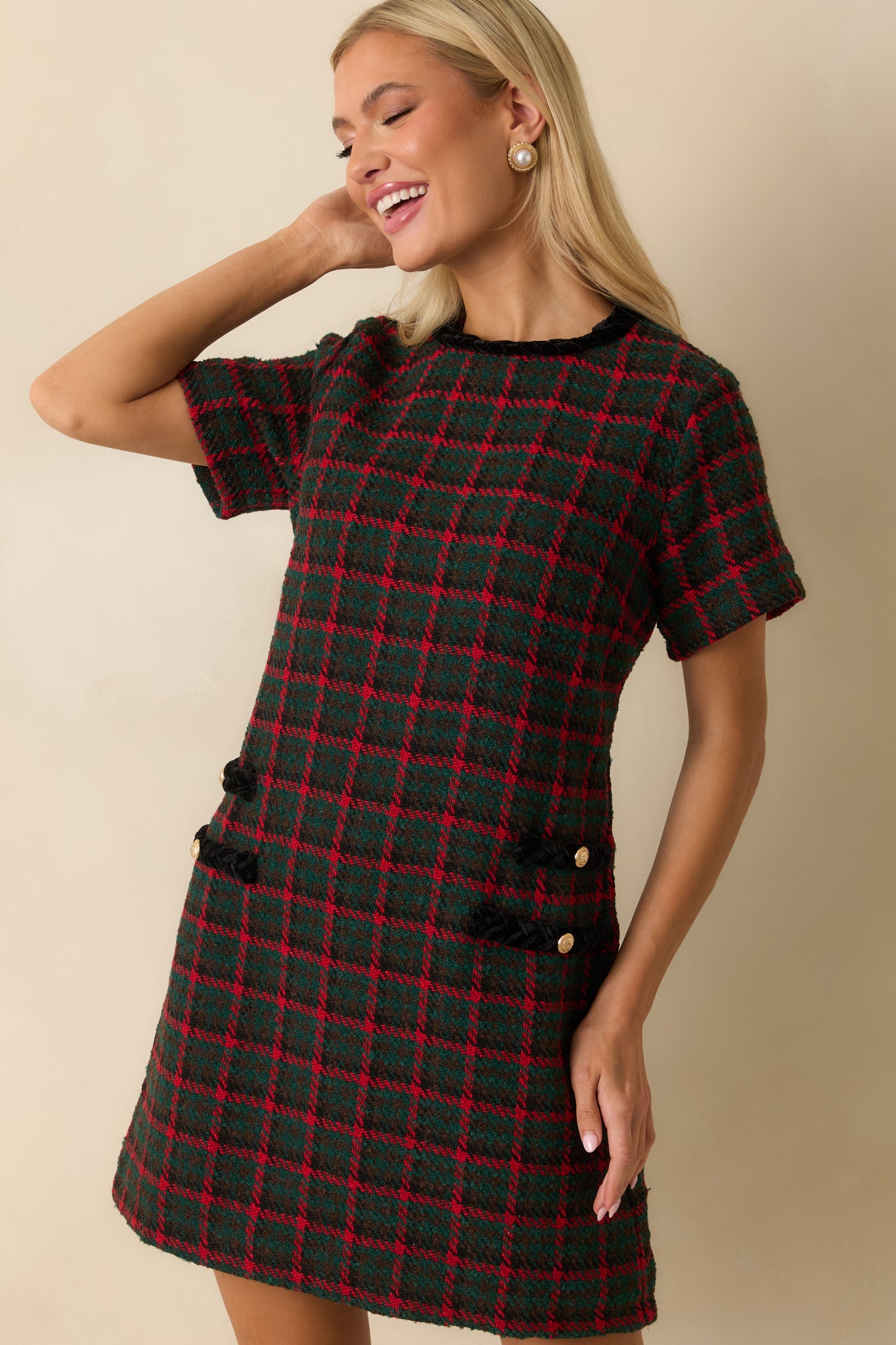 Contrast-trimmed pocket showcased with its gold button detail against the green and red plaid tweed.
