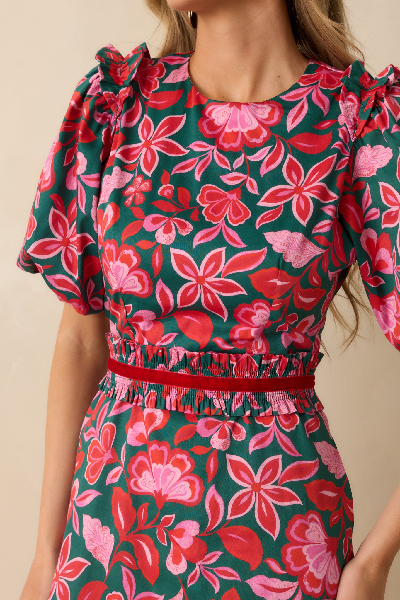 A close view reveals the green and pink floral print, puff sleeve construction, and elasticized waist details on crisp cotton.