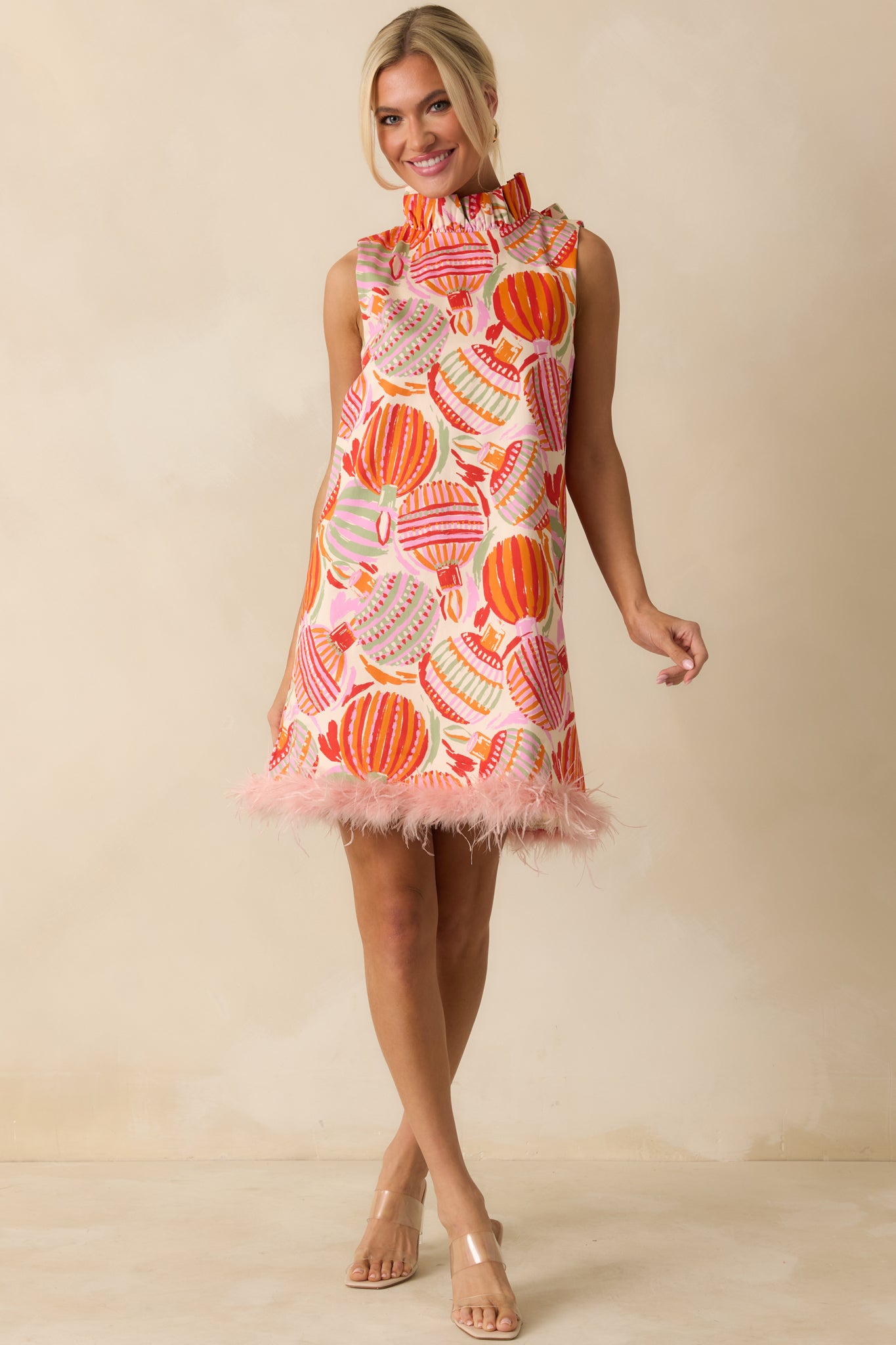 The mini dress shows off its multicolor ornament print with a clean straight silhouette and playful ruffled mock neckline.