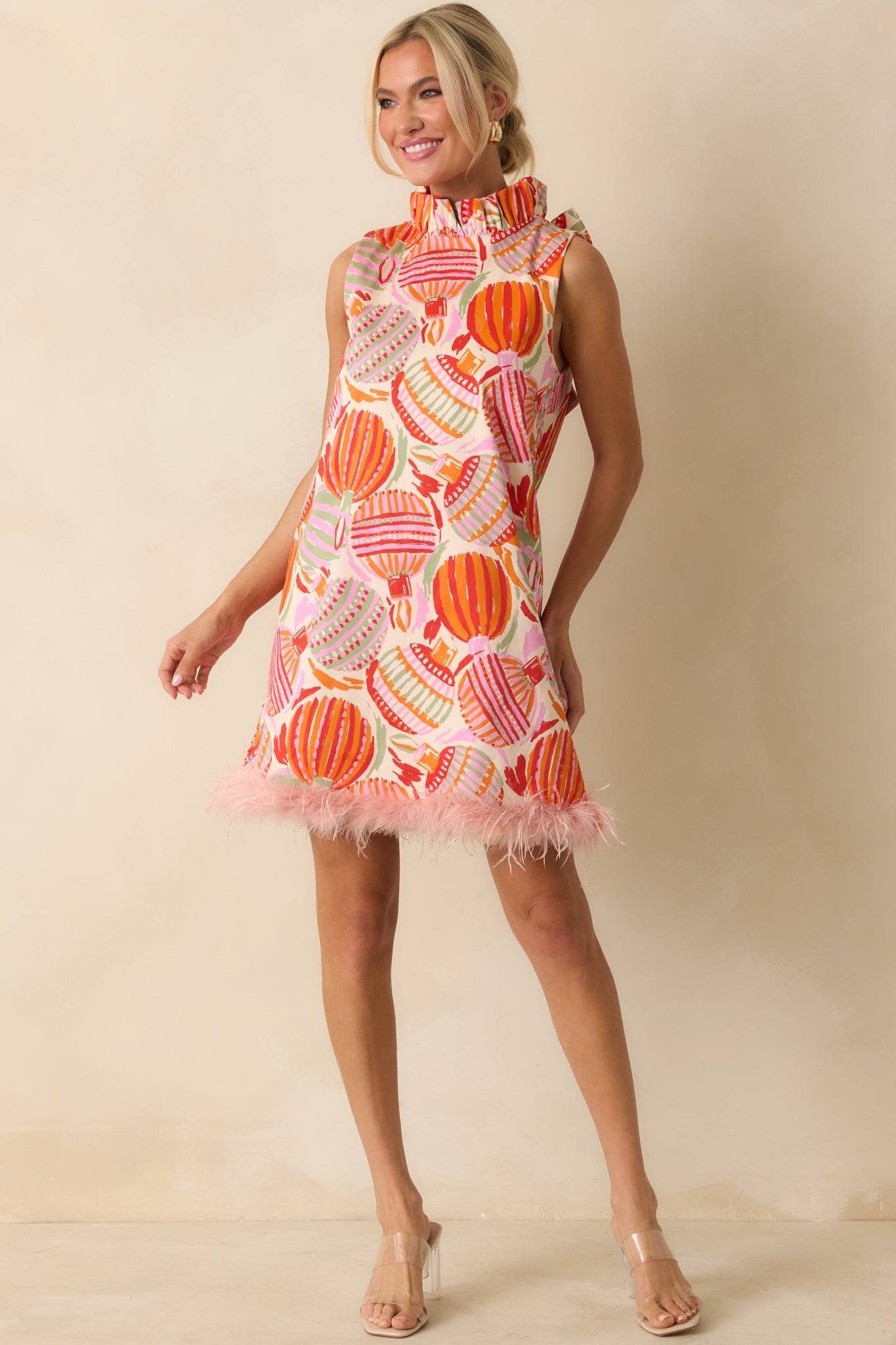 The dress highlights its woven cotton fabric and bold ornament pattern, finished with a soft feather-trimmed hem.