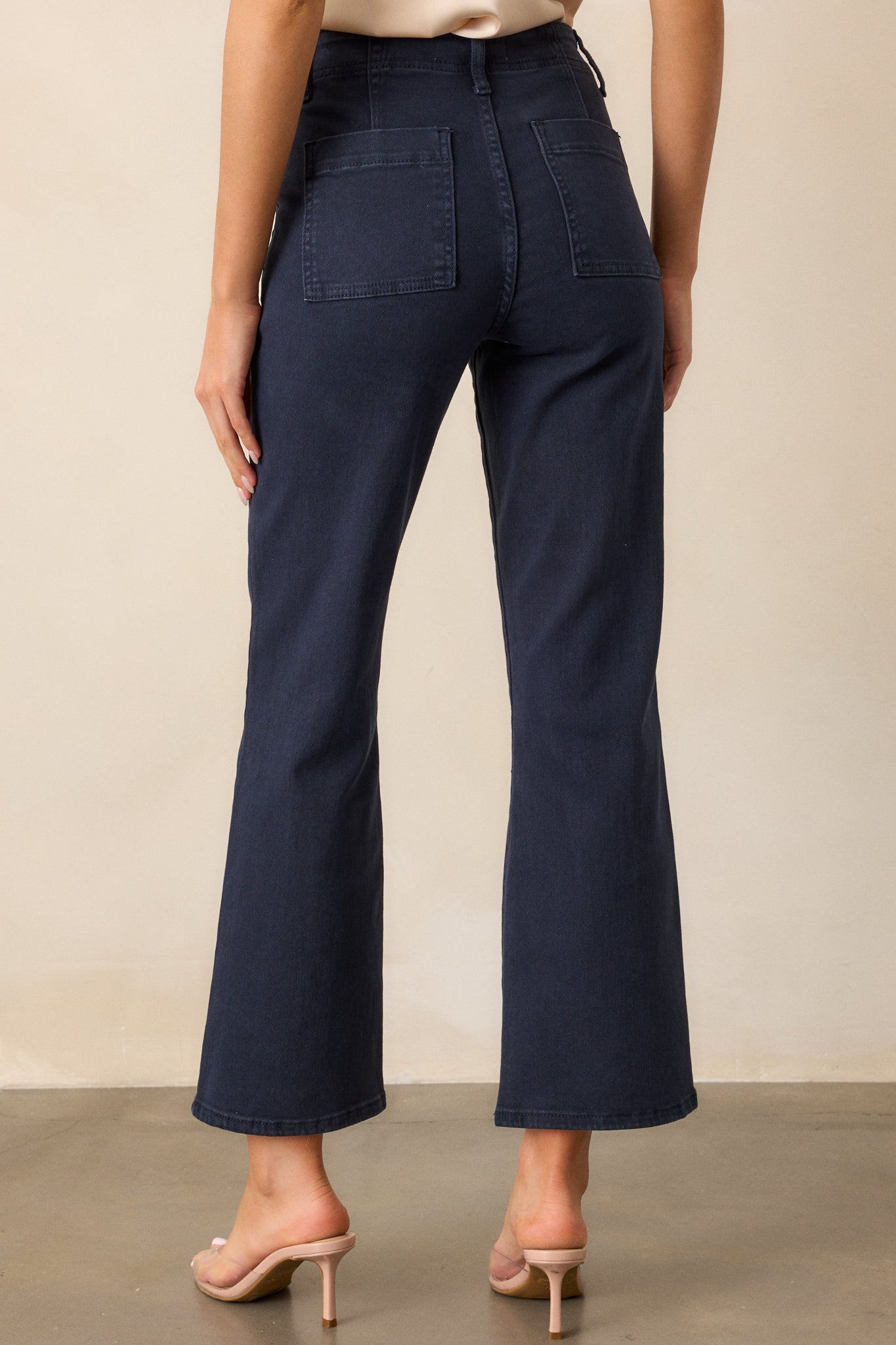 A back view of the navy jeans displaying the high waist and streamlined design with visible pockets.