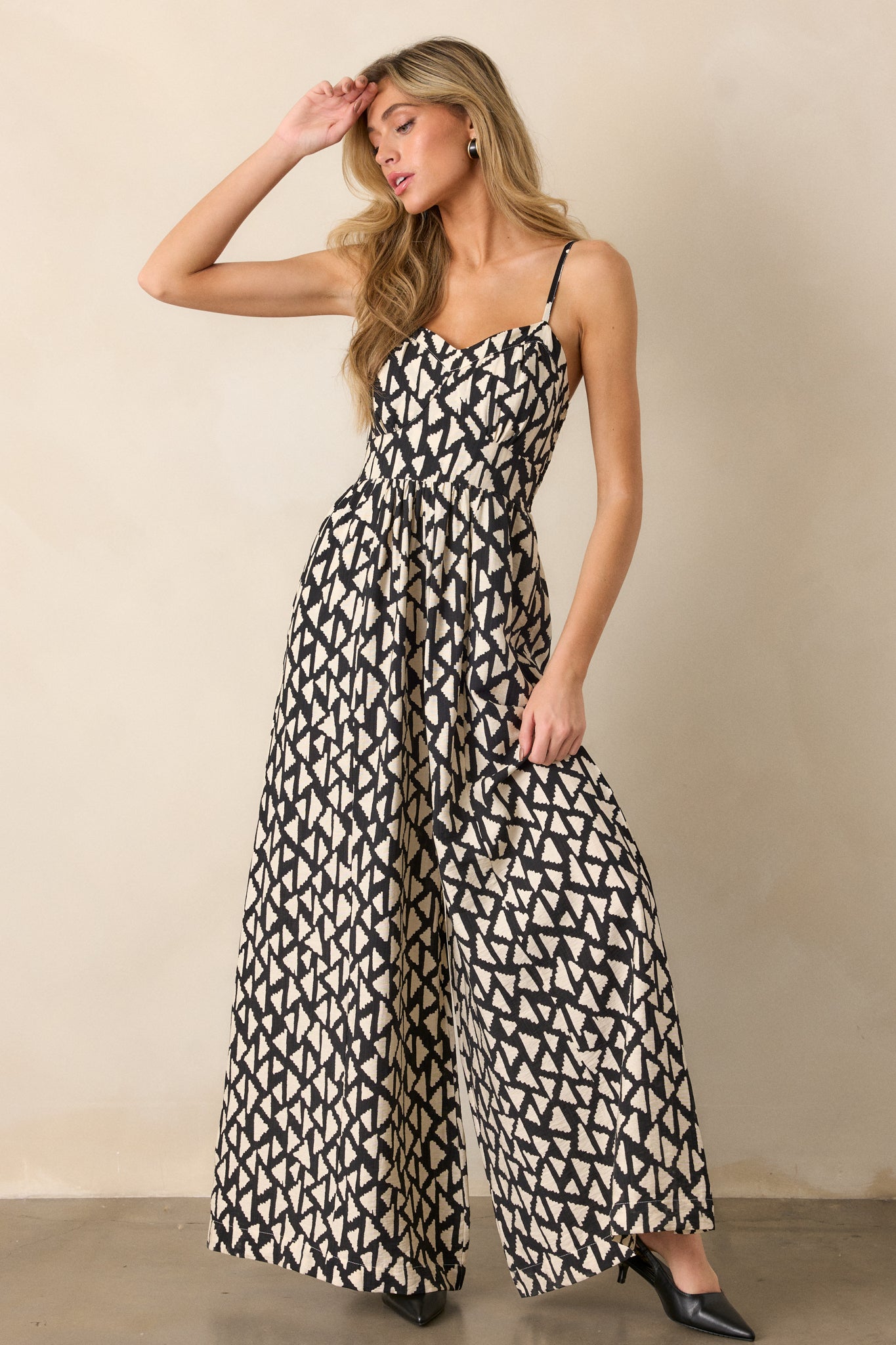 A posed shot of the black jumpsuit showing the drape of the wide leg pants and structured top.