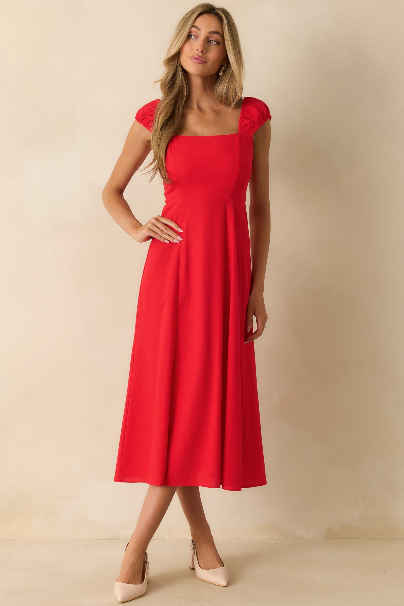 Square-neck red midi dress with smocked sleeves, a high slit, and a full flowy skirt.