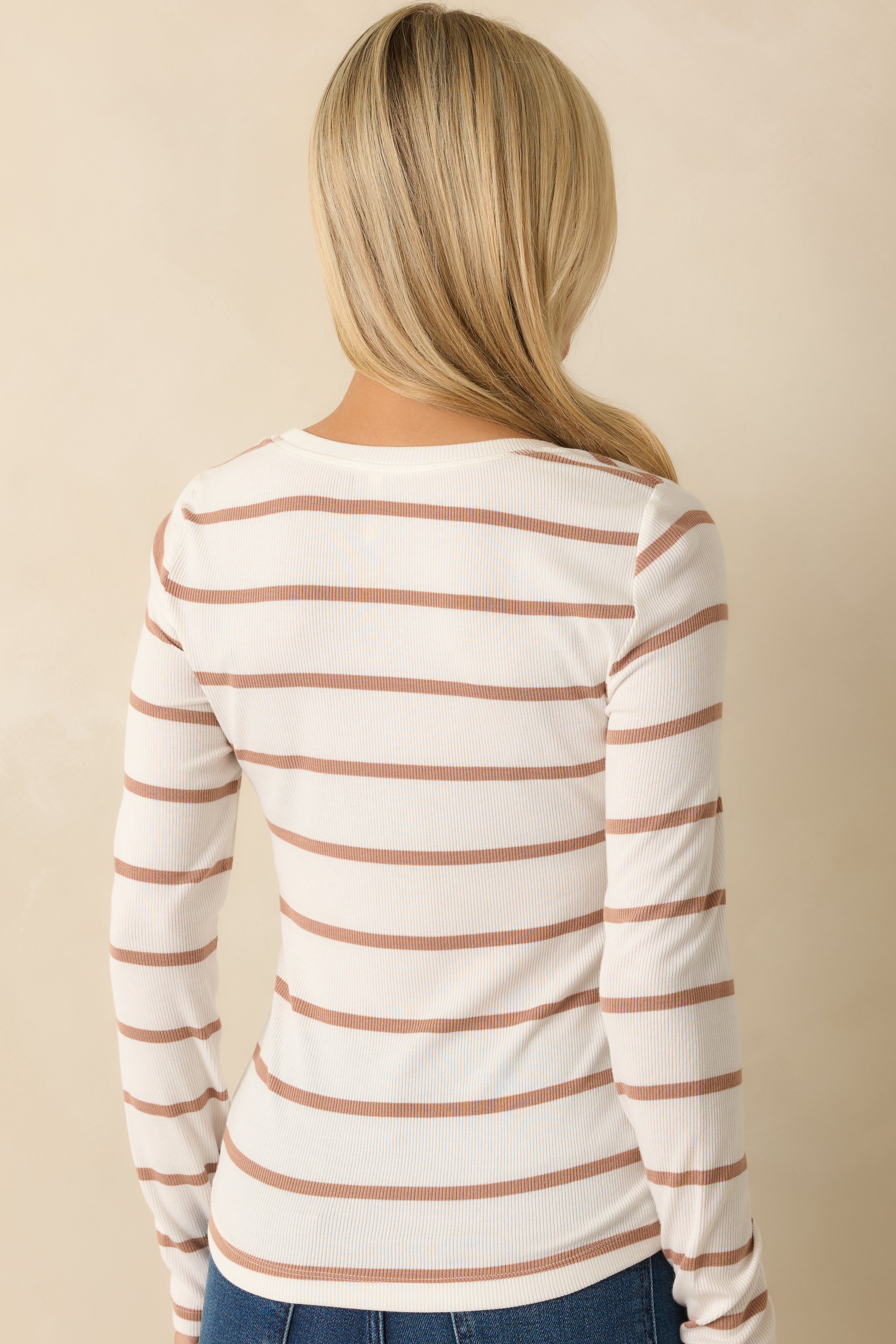 Rear view of the white and caramel striped top displaying the long sleeves and consistent stripe design.