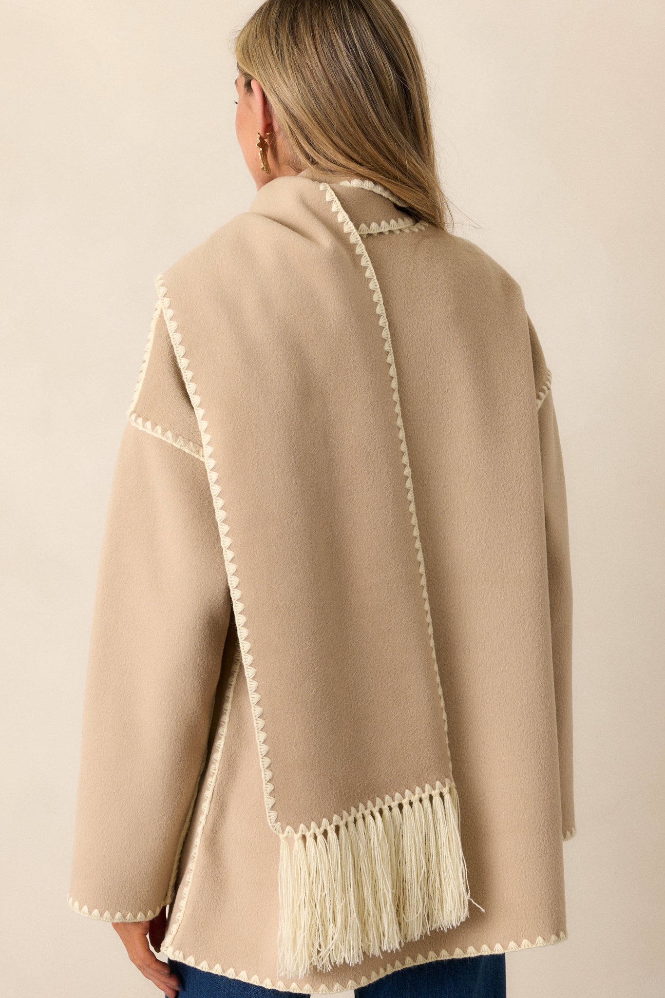 Back view of the taupe coat showing the straight back, long sleeves, and blanket stitch hem at the back.