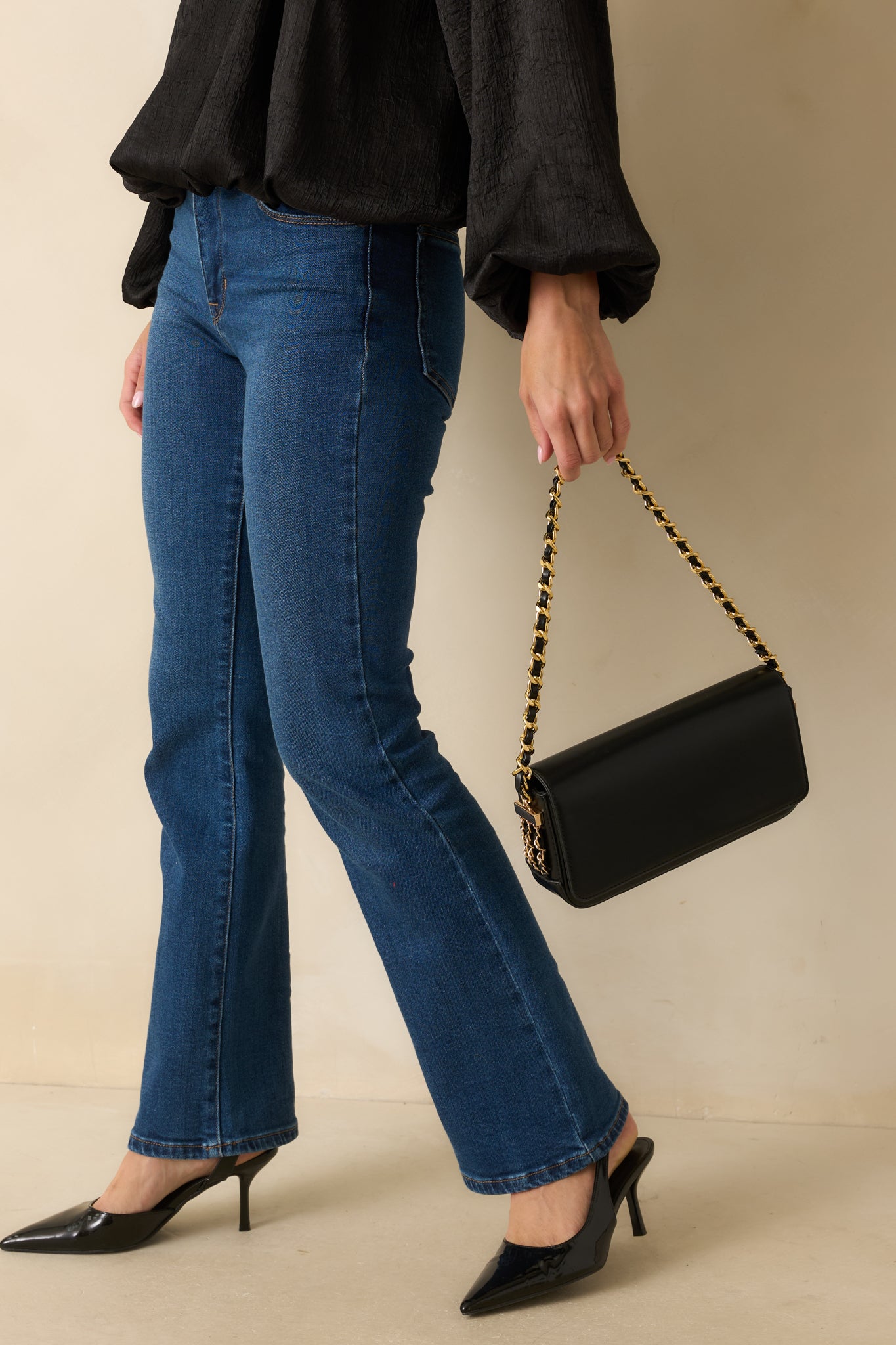 Angled view of the black baguette-style handbag highlighting the decorative chain detailing along the sides.