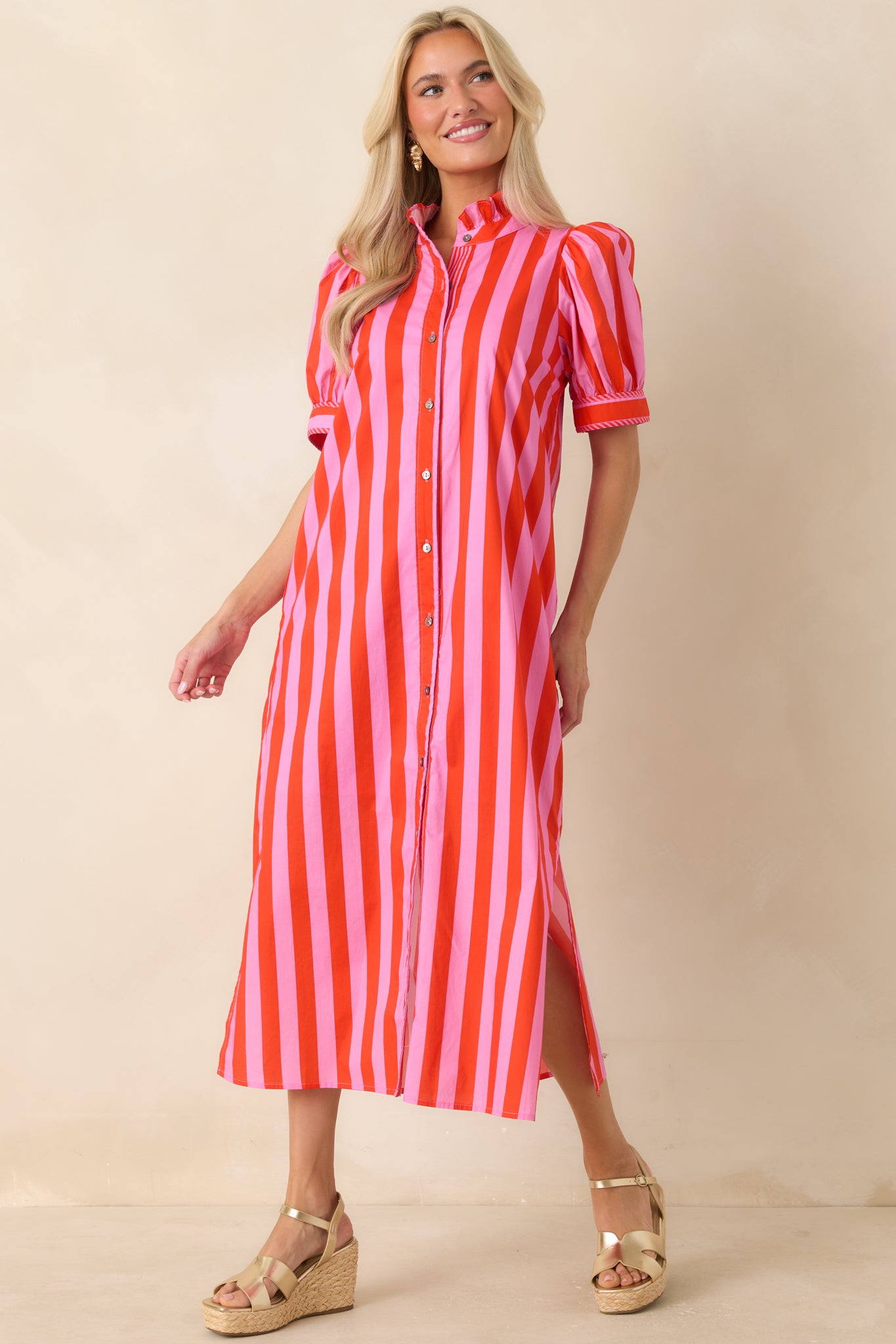 Pink and red vertical stripe midi dress featuring a button front design, short puff sleeves, side pockets, and lightweight cotton fabric.