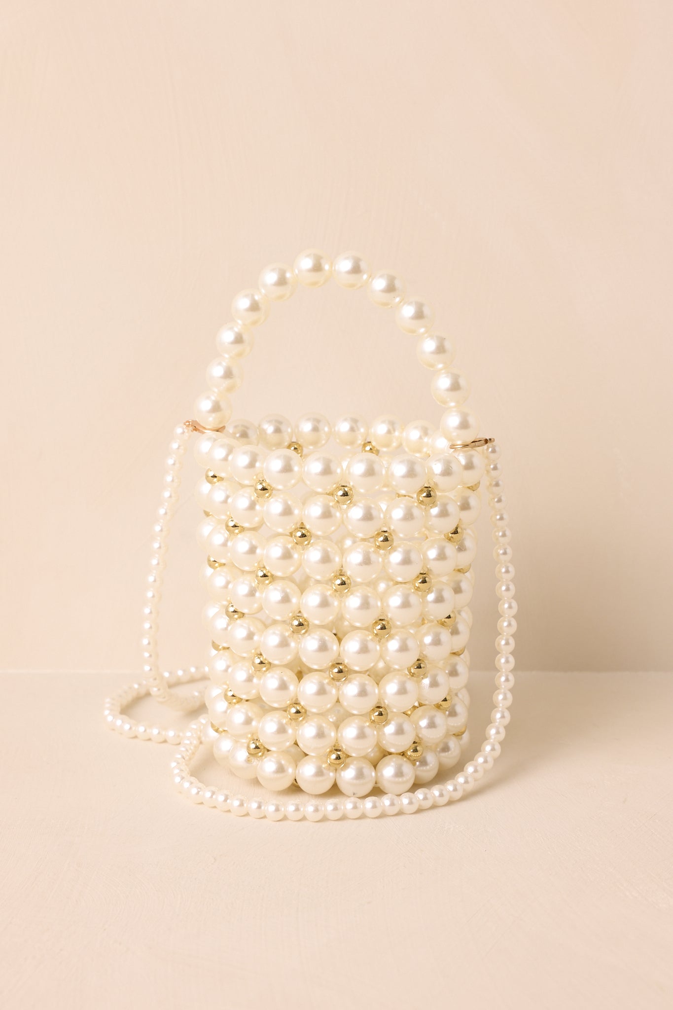 Full view of the ivory pearl clutch showcasing its cylindrical shape and structured pearl handle.