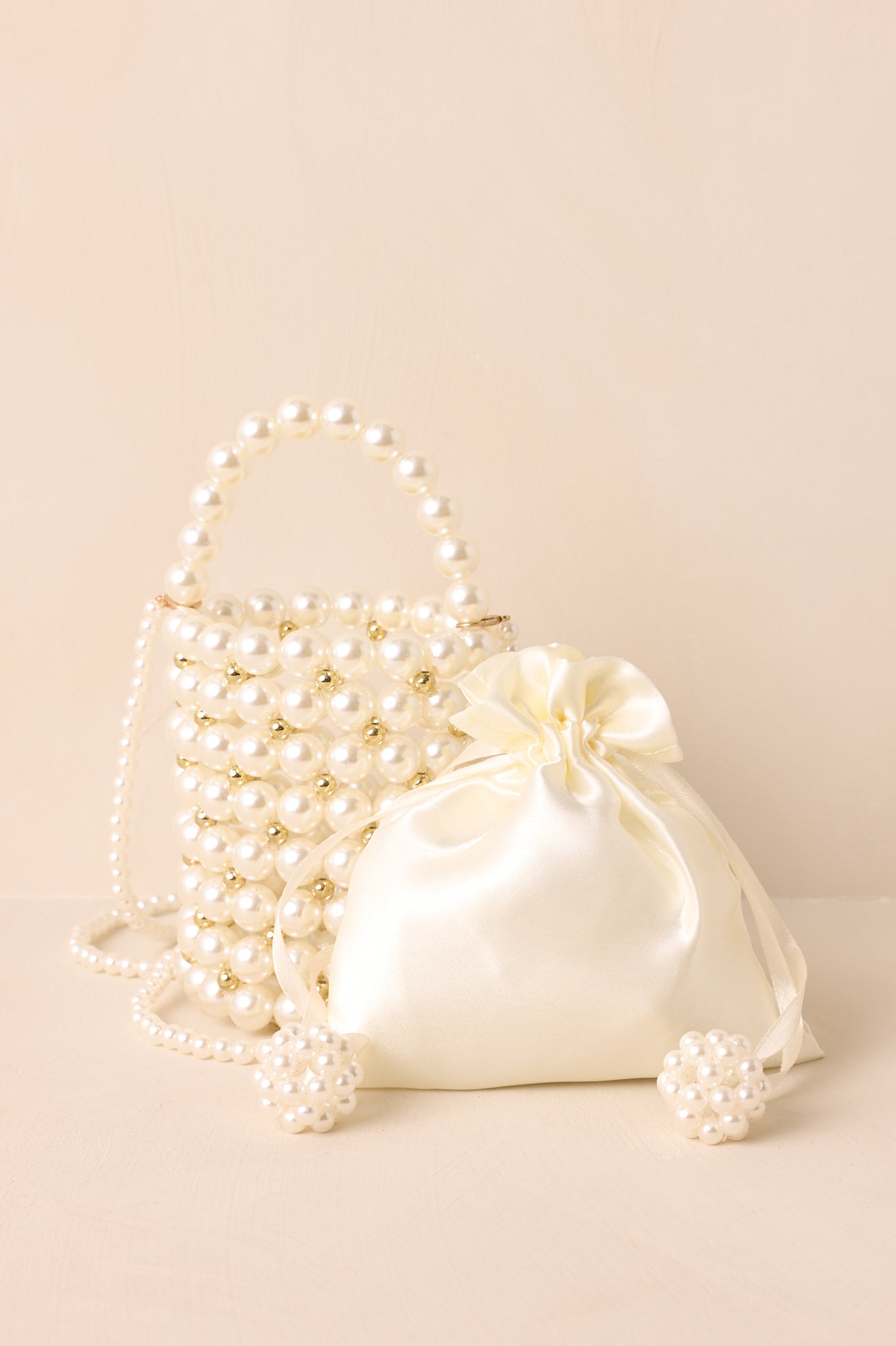 Full-body image highlighting the optional pearl crossbody strap and gold pearl accents at the base.
