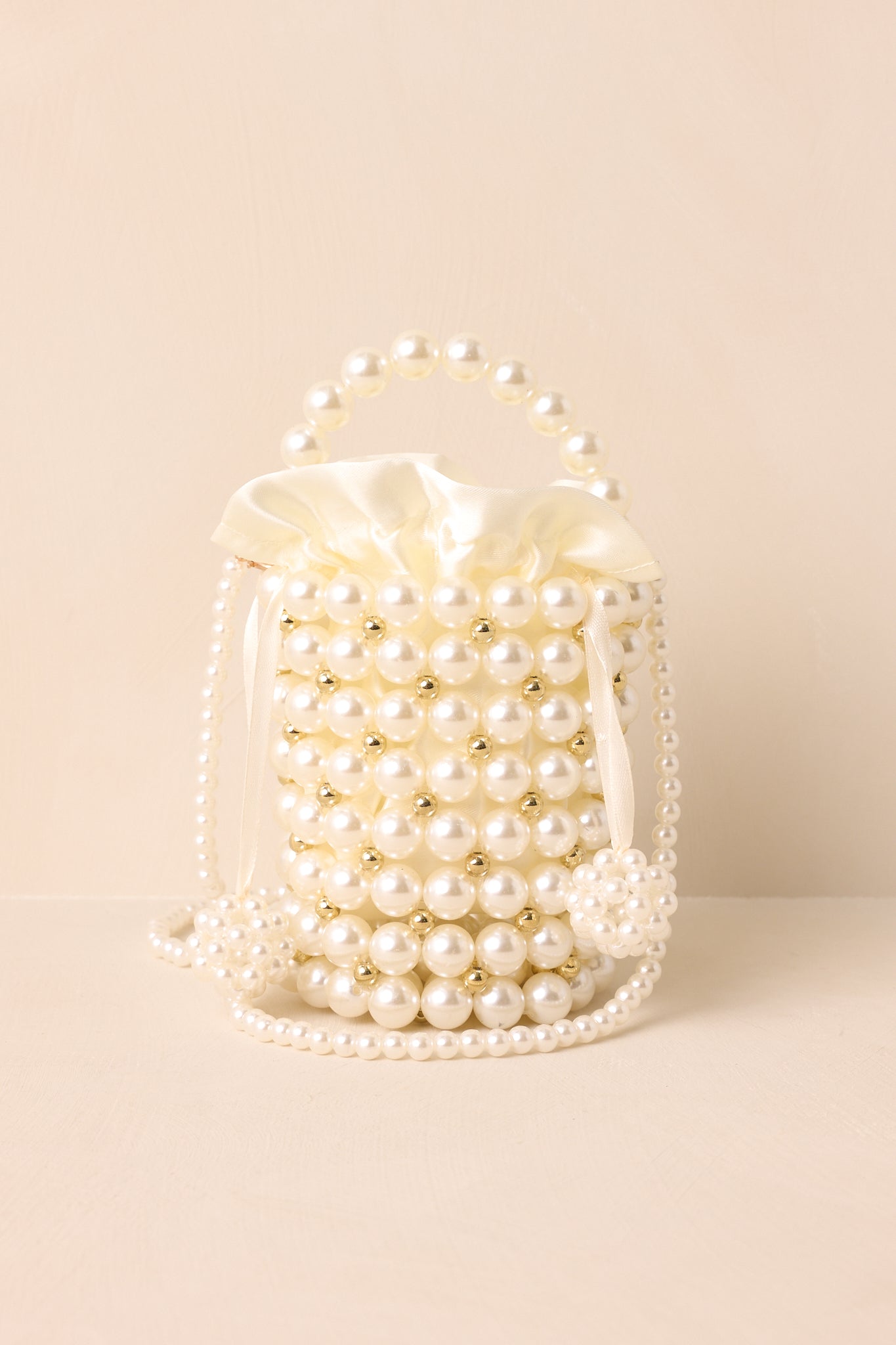 Cropped image focusing on the alternating ivory and gold faux pearls and the detailed cylindrical construction.