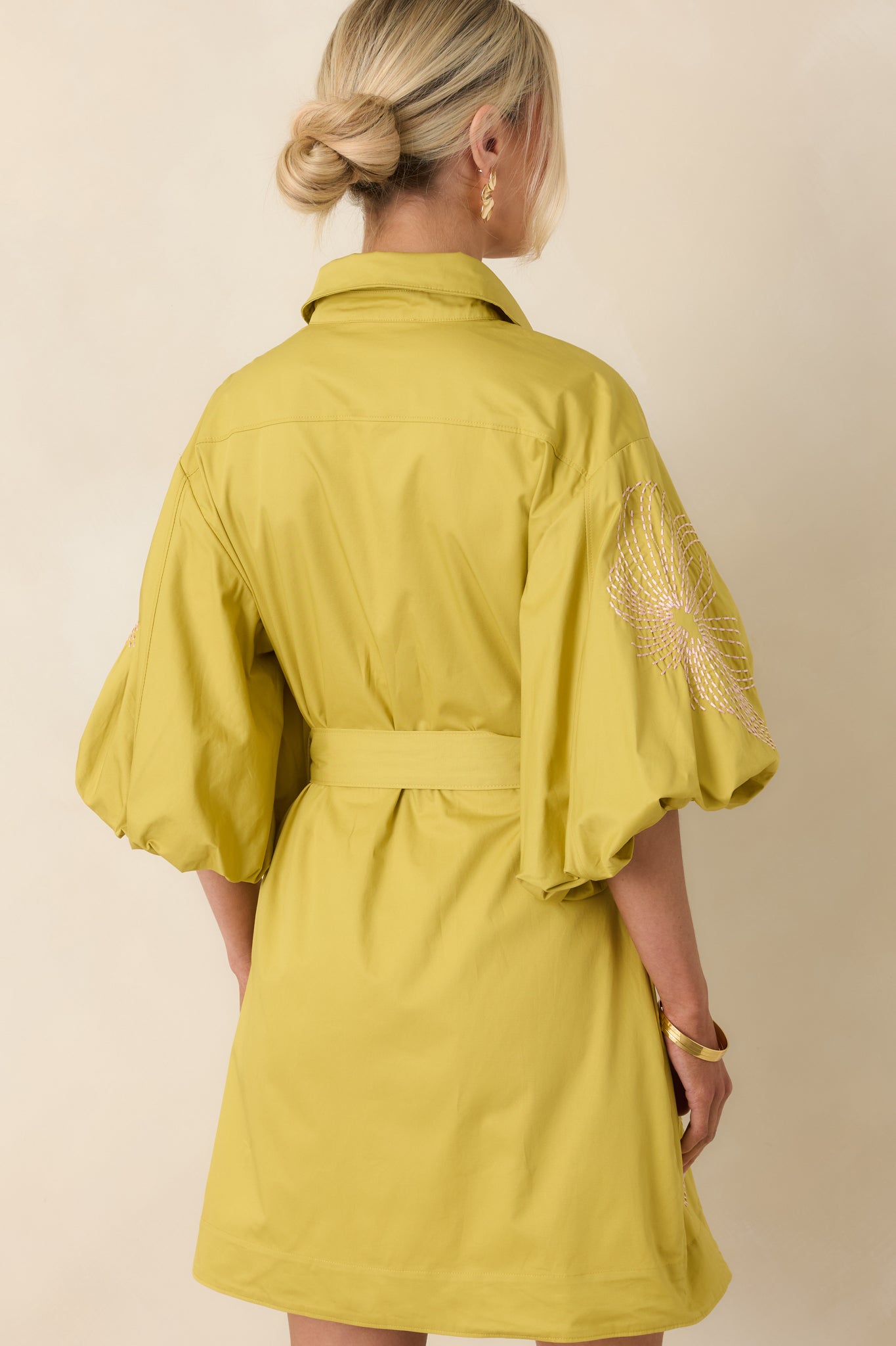 Rear view of cotton mini dress with puff sleeves, defined waist, and soft embroidered detailing.