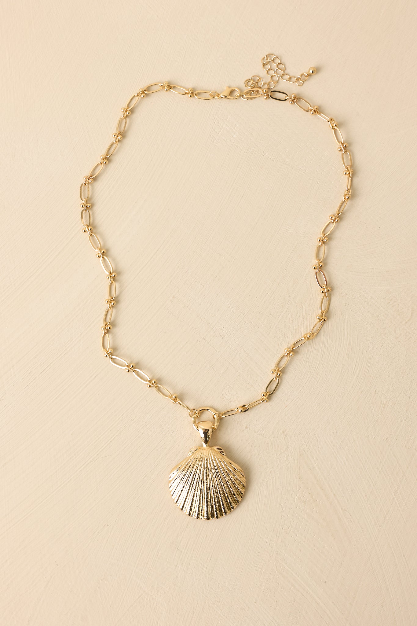 Close-in crop highlighting the shell pendant and polished elongated chain links.