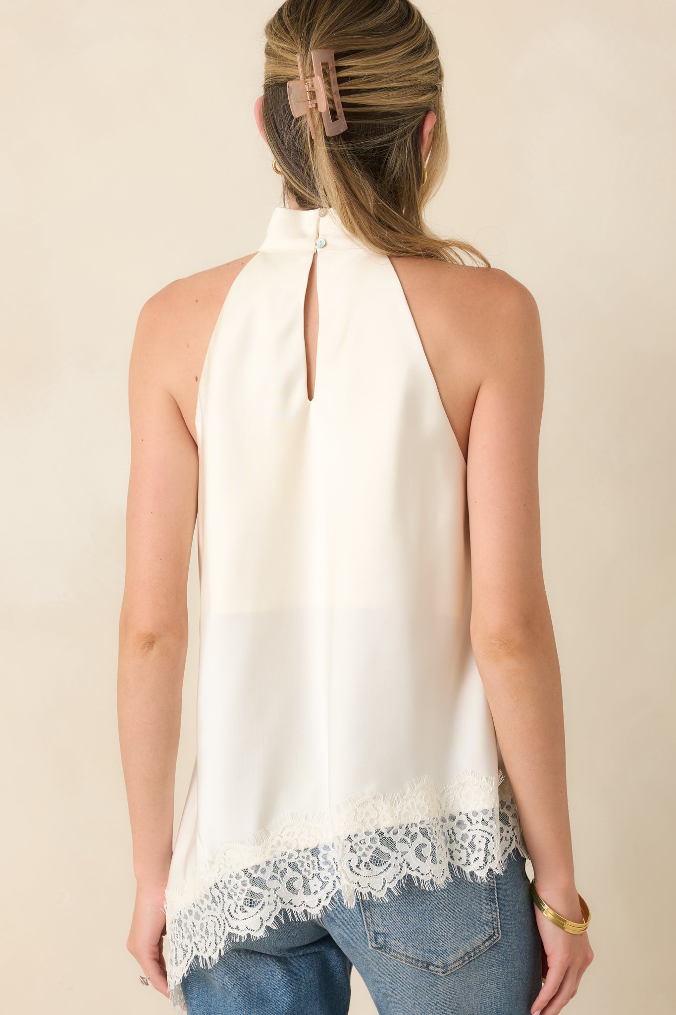 Back view of the ivory halter top featuring a keyhole button closure and fluid asymmetrical silhouette.