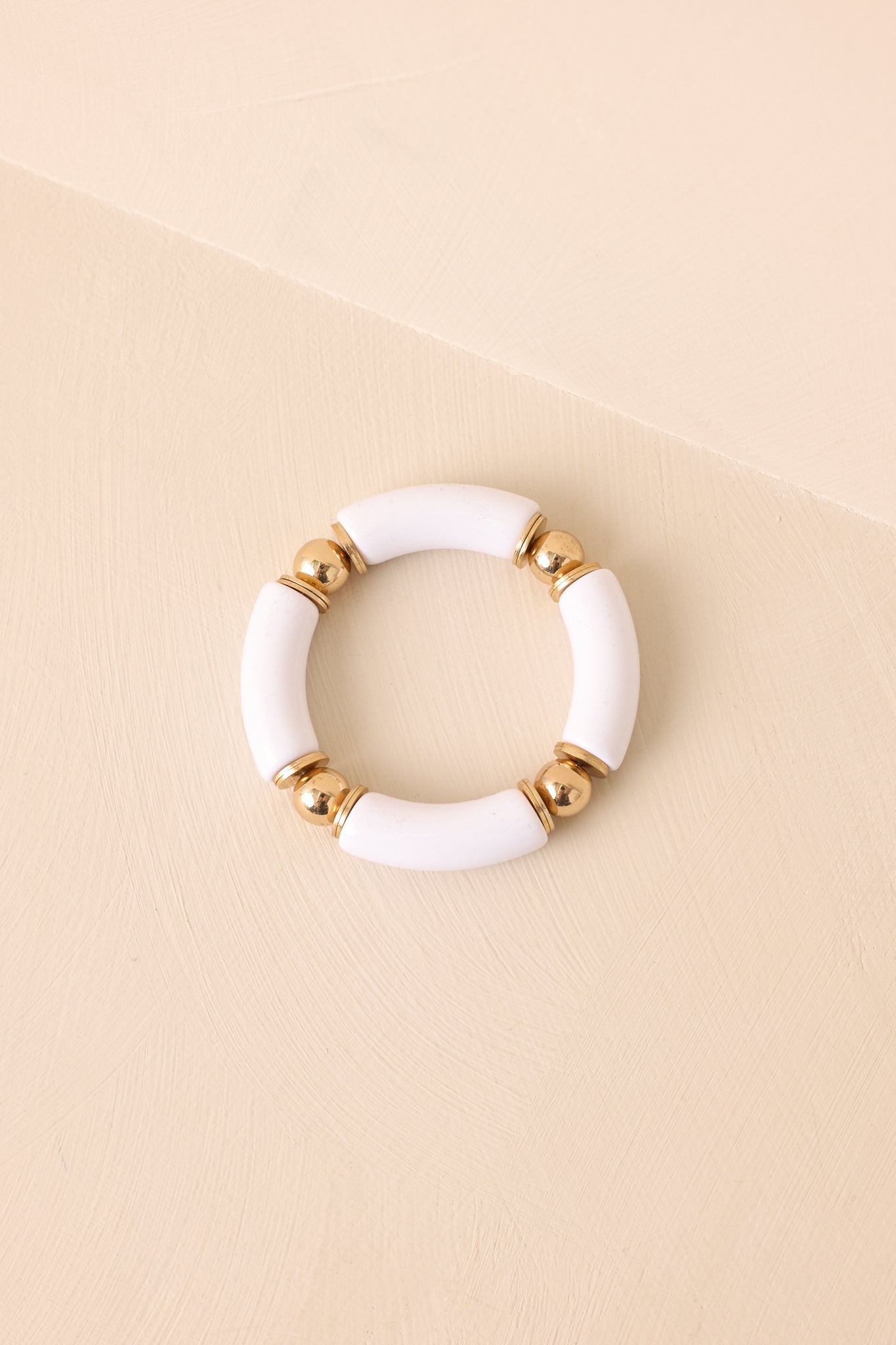 Bracelet laid flat against a beige background, emphasizing the stretchable elastic design, gold hardware, and the stylish mix of bead sizes and finishes.
