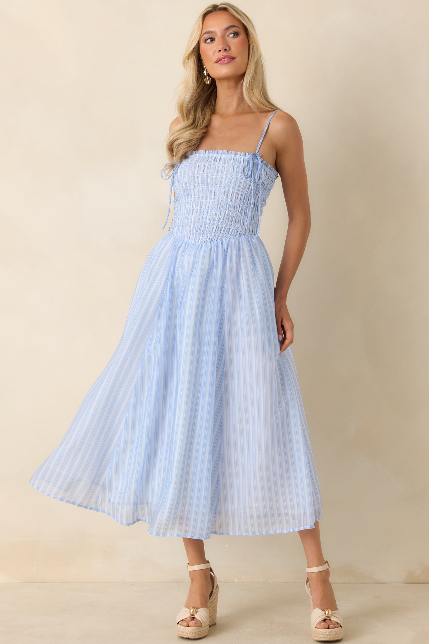 Striped midi dress showcasing a fitted smocked top and a relaxed, airy midi-length silhouette.