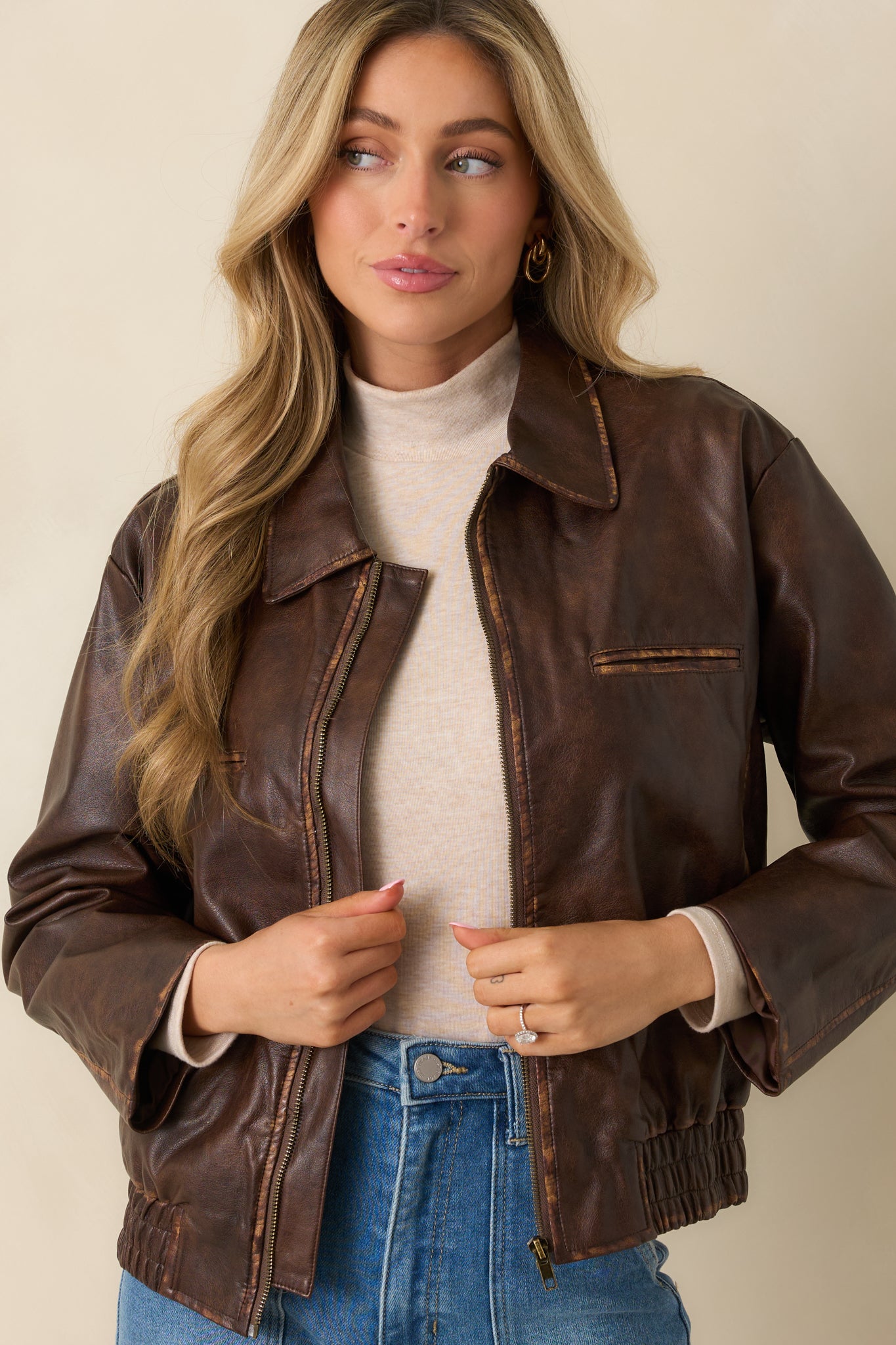 Close view highlighting the front zip closure and worn-in brown leather texture.