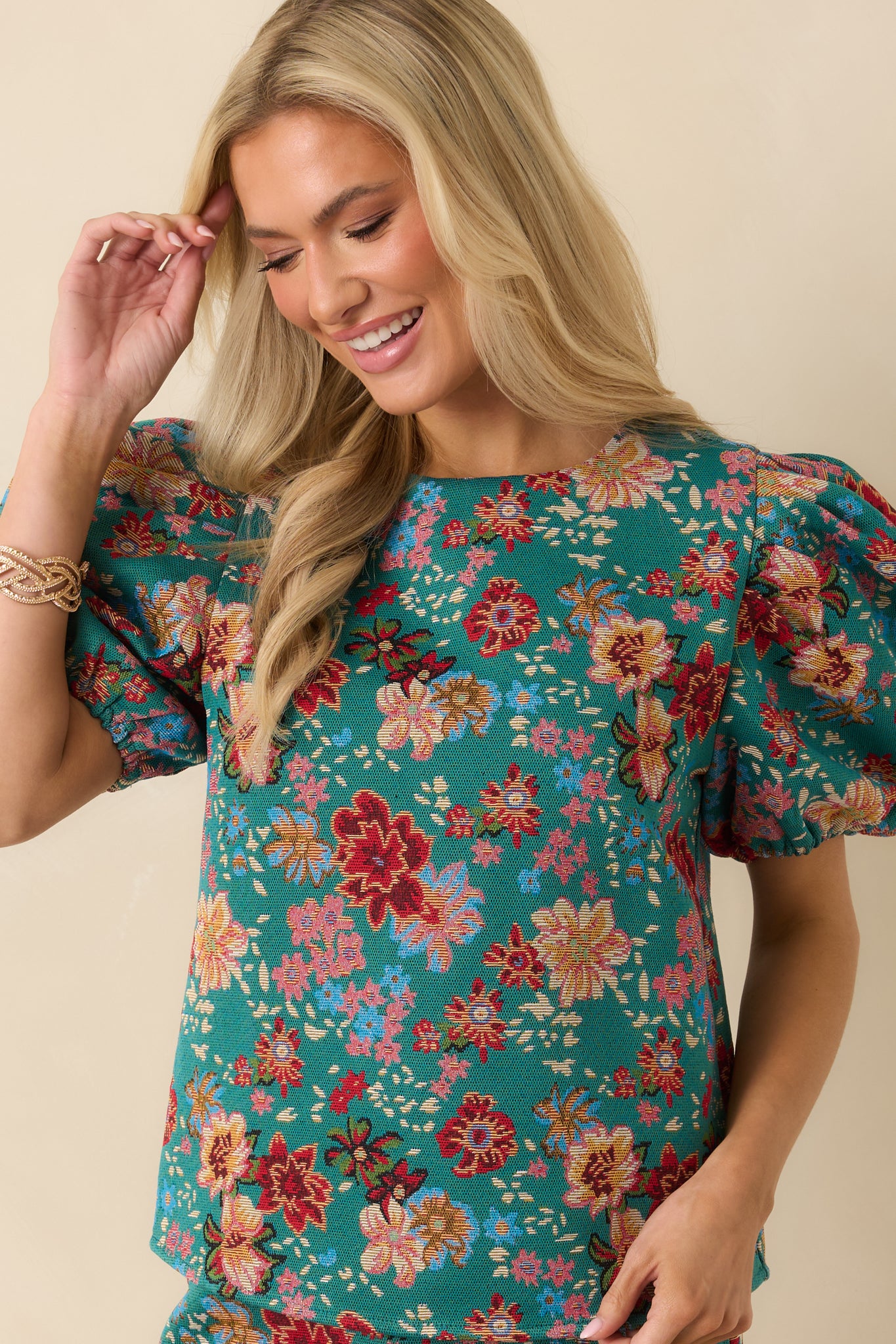 Teal-green woven top with an allover multicolor floral pattern, classic crew neckline, and short puff sleeves.