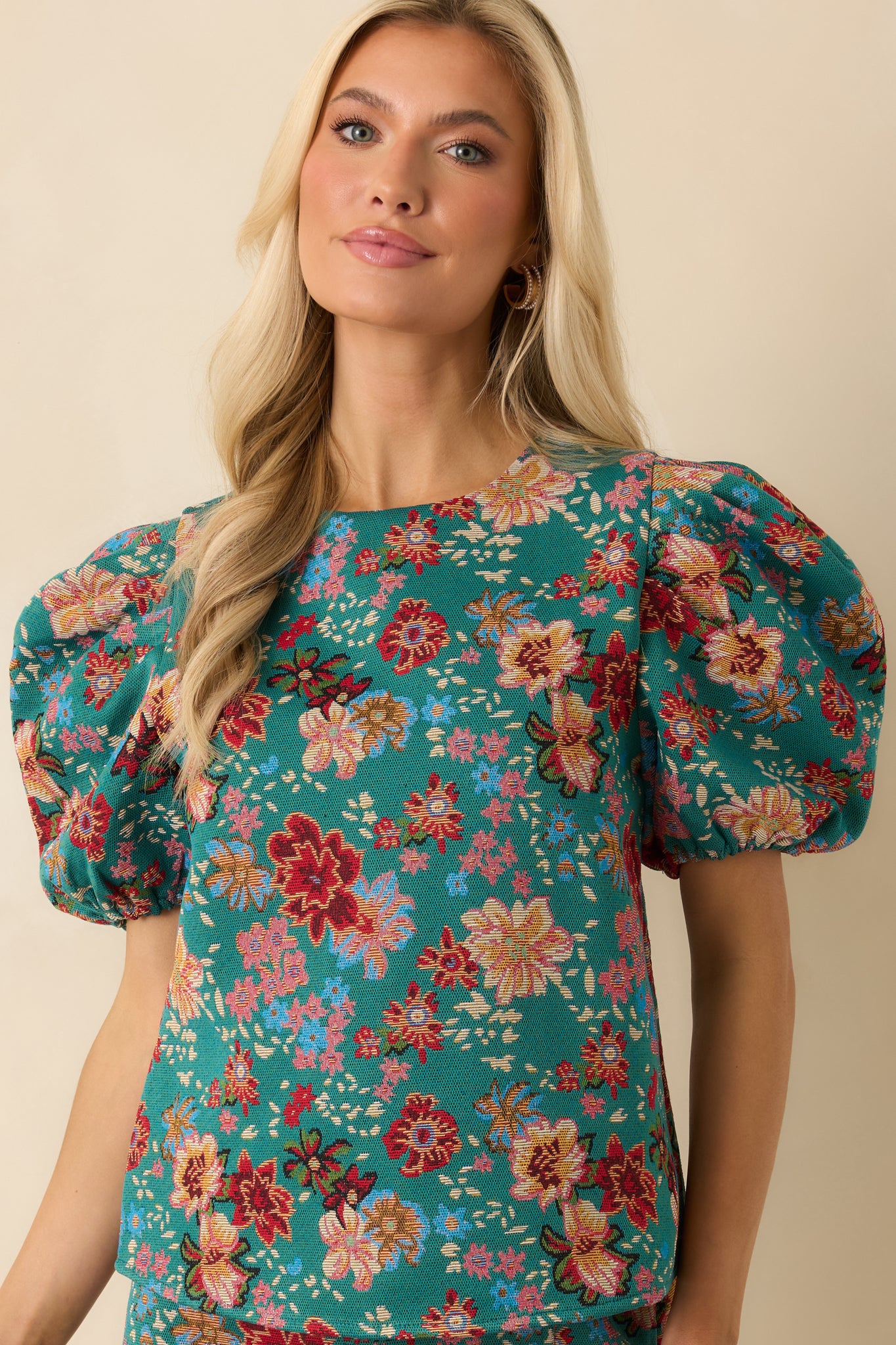 Cropped front view of the teal-green top showing the floral print, gathered shoulder detail, and smooth fabric.