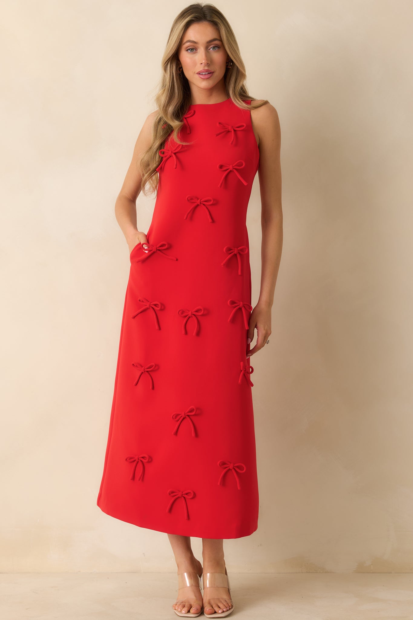 Front view of a red maxi dress highlighting the bow accents along a sleek, straight silhouette and crew neckline.