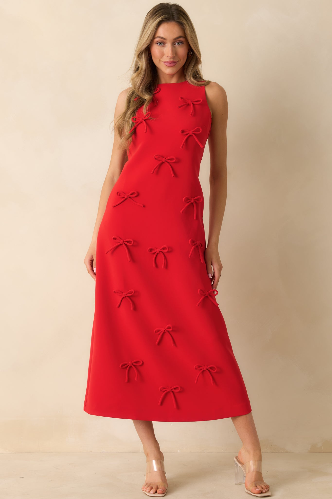 Full-length red maxi dress showing the clean straight silhouette and playful bow appliqués along the fabric.