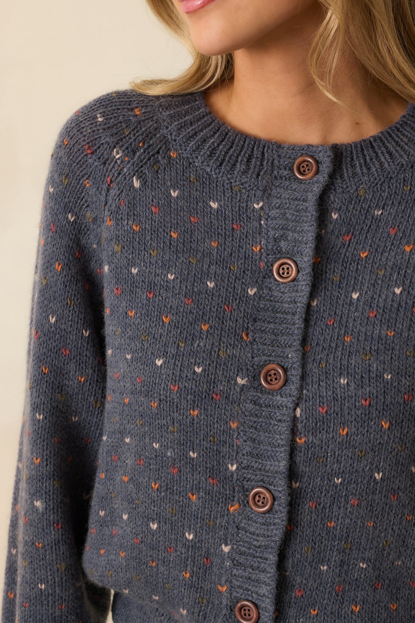Close-up of the knit fabric and heart-patterned buttons, showing fine texture and cozy feel.