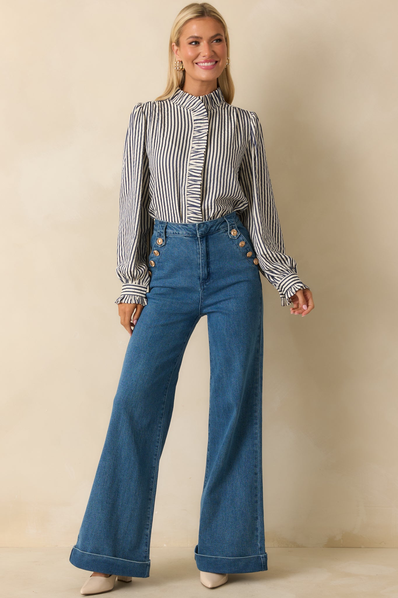 High-rise indigo jeans with wide cuffed legs and functional gold-tone buttons along the side.