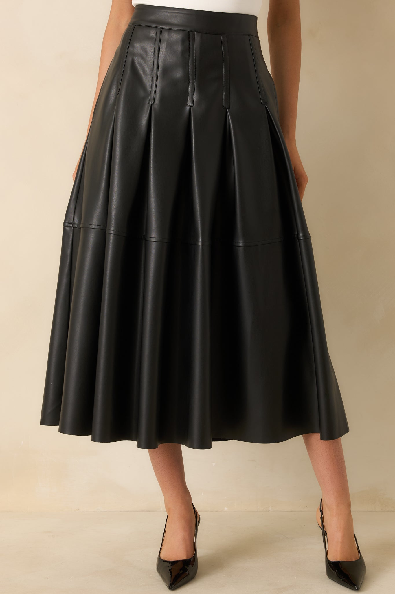 Cropped view highlighting the vertical pleats and clean waistband construction of the skirt.