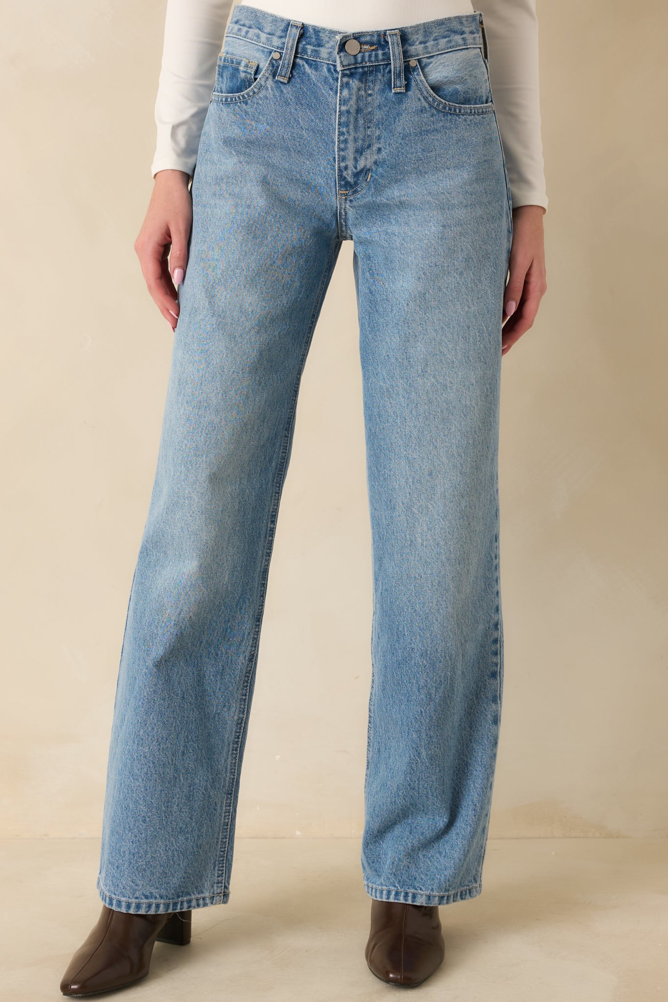 Midsection and upper legs of jeans highlighting straight leg cut and light wash.