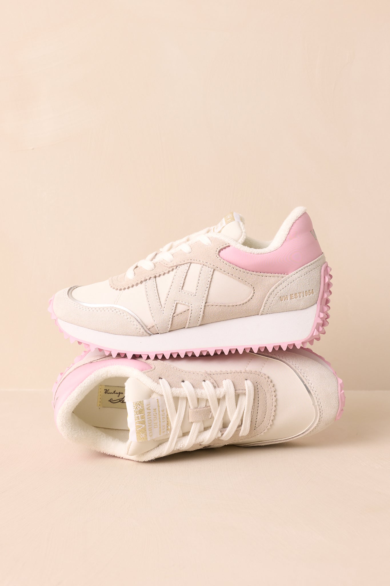 A full shot of the ivory and taupe sneakers, highlighting the thick heel and baby pink sole.
