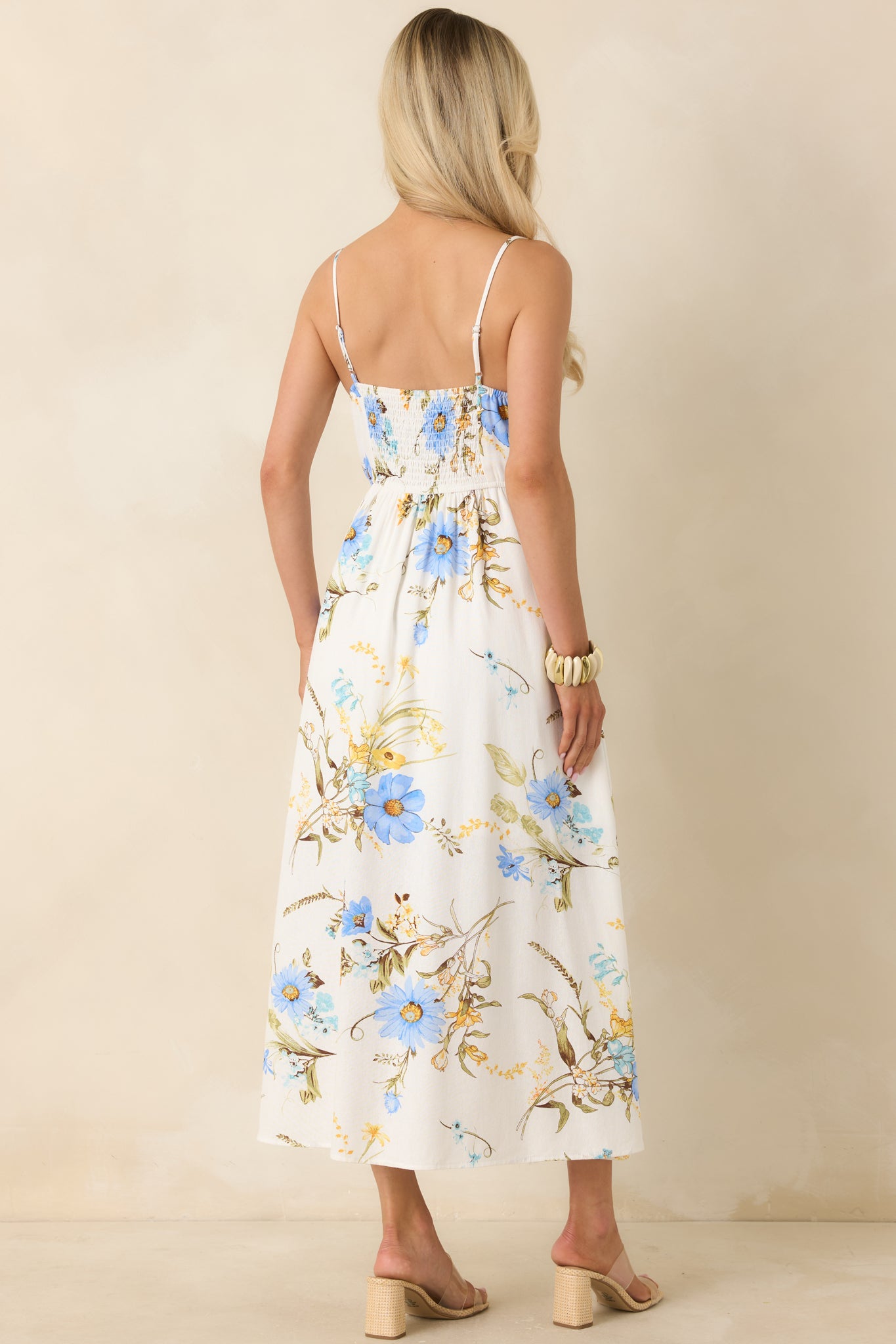 Rear view of blue floral midi dress highlighting smocked back panel, adjustable straps, and softly gathered skirt.