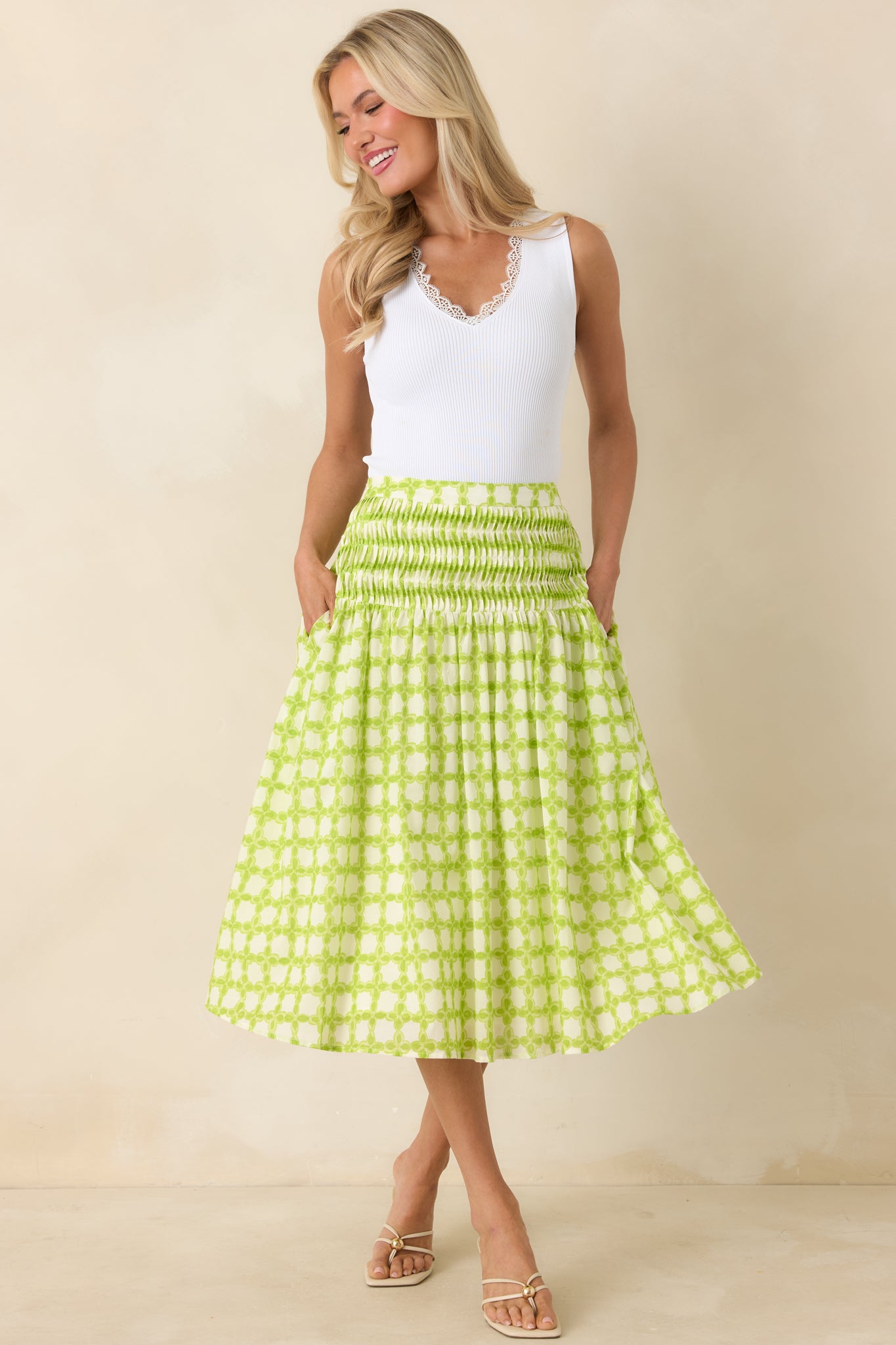 White ribbed tank featuring a sleek fitted shape, soft stretch knit fabric, and a V-neckline finished with scalloped lace trim.