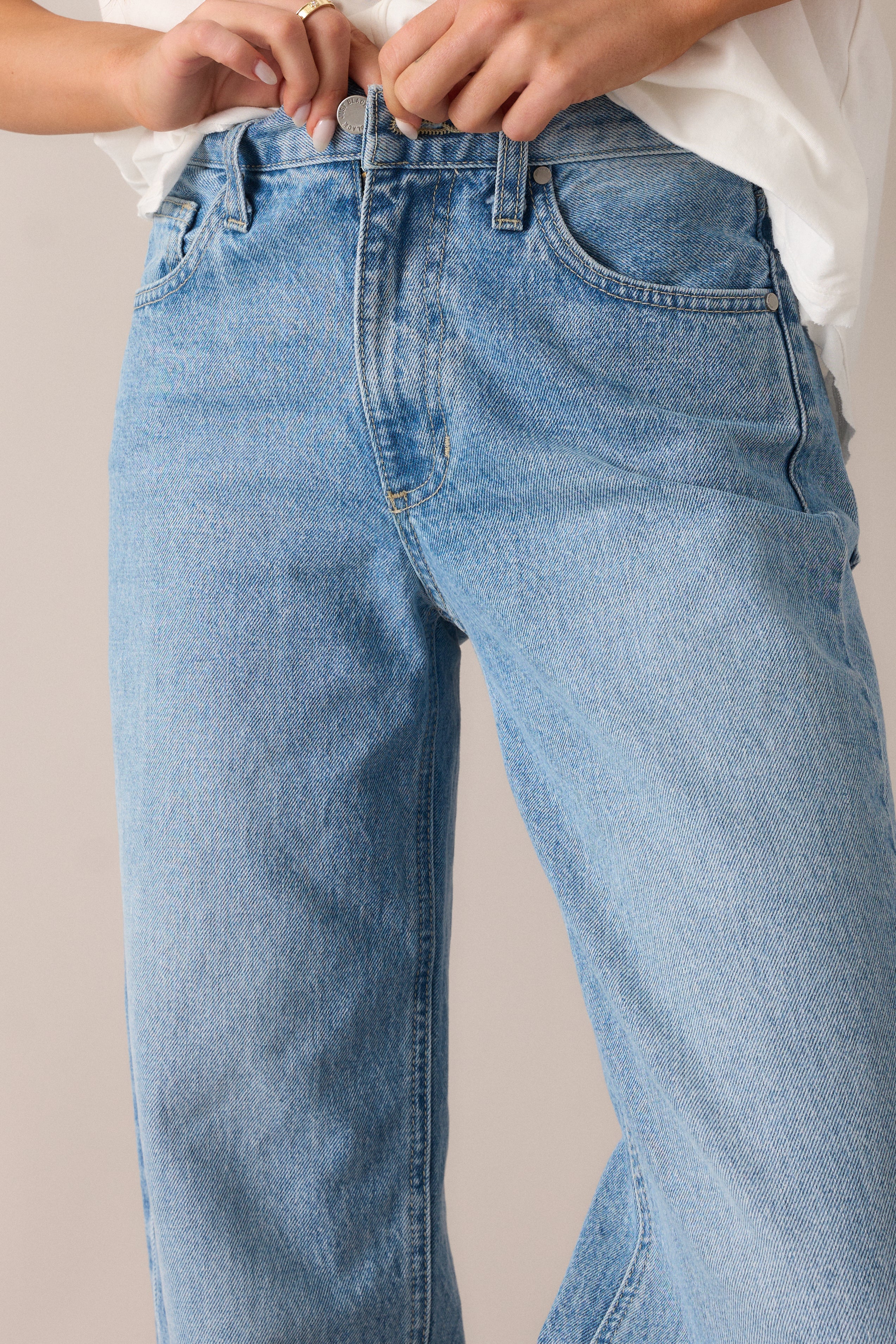 A focused view of the button & zip closure, emphasizing the subtle texture of the light wash fabric and the relaxed fit that gives these jeans an effortless vibe.