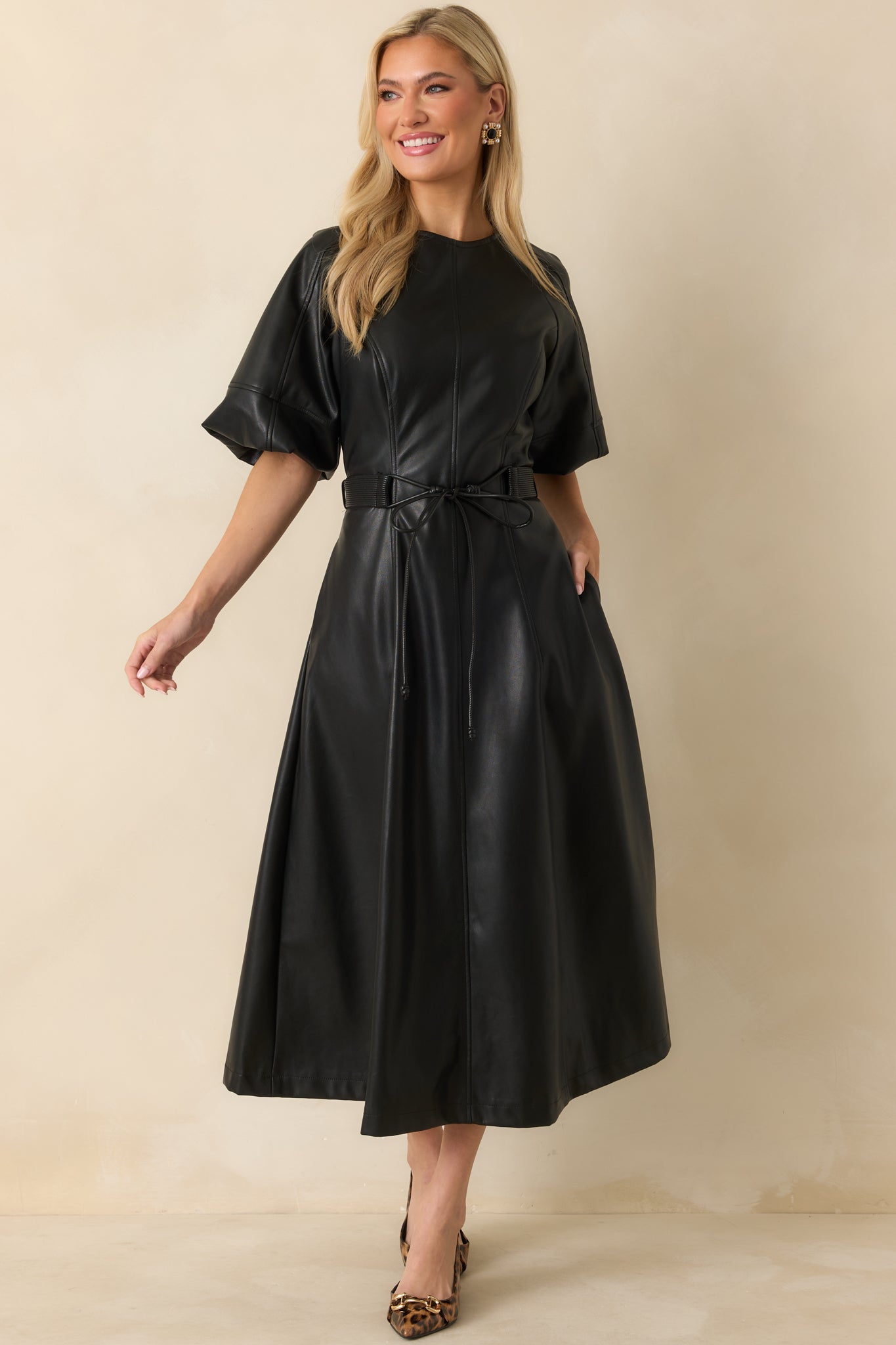Black faux leather midi dress with a soft sheen finish and clean vertical seaming throughout.