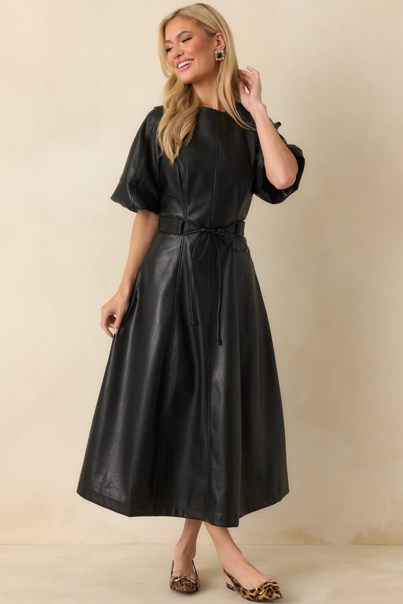 Black A-line midi dress designed with smooth faux leather and a fluid, flattering drape.